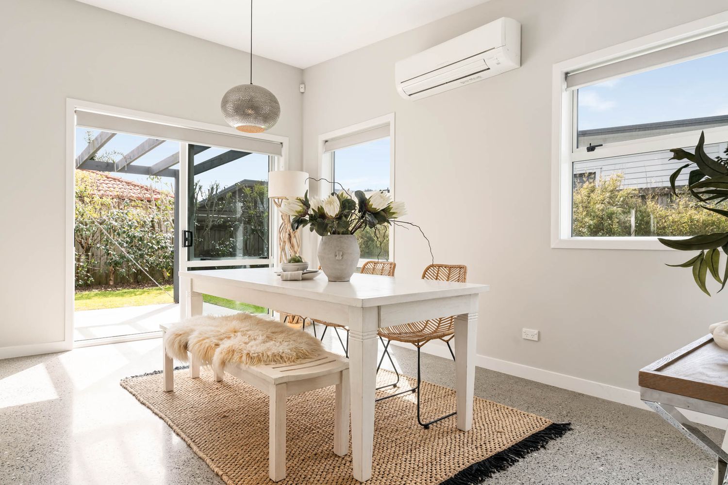Modern white interior room with natural light streaming through multiple windows and skylight features in a minimalist design.