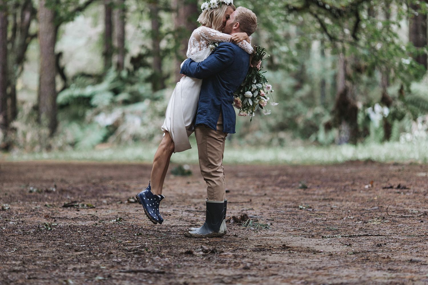 A couple embraces while standing on a forest path, creating an intimate moment in nature.