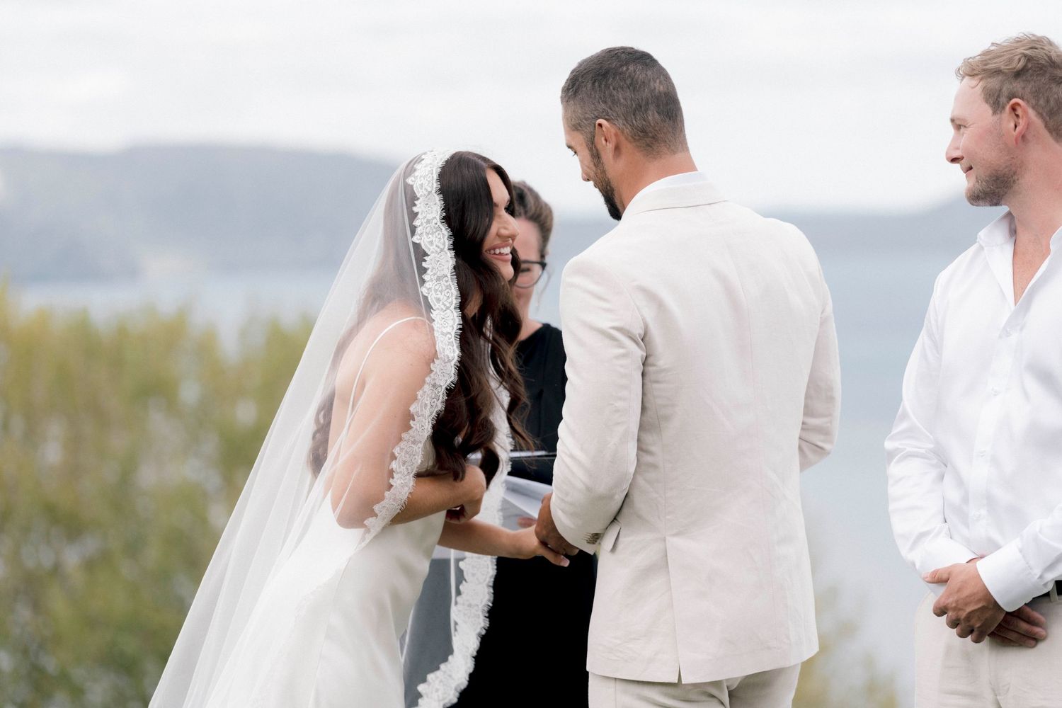Romantic outdoor wedding scene with couple sharing an intimate moment by a serene coastal backdrop.