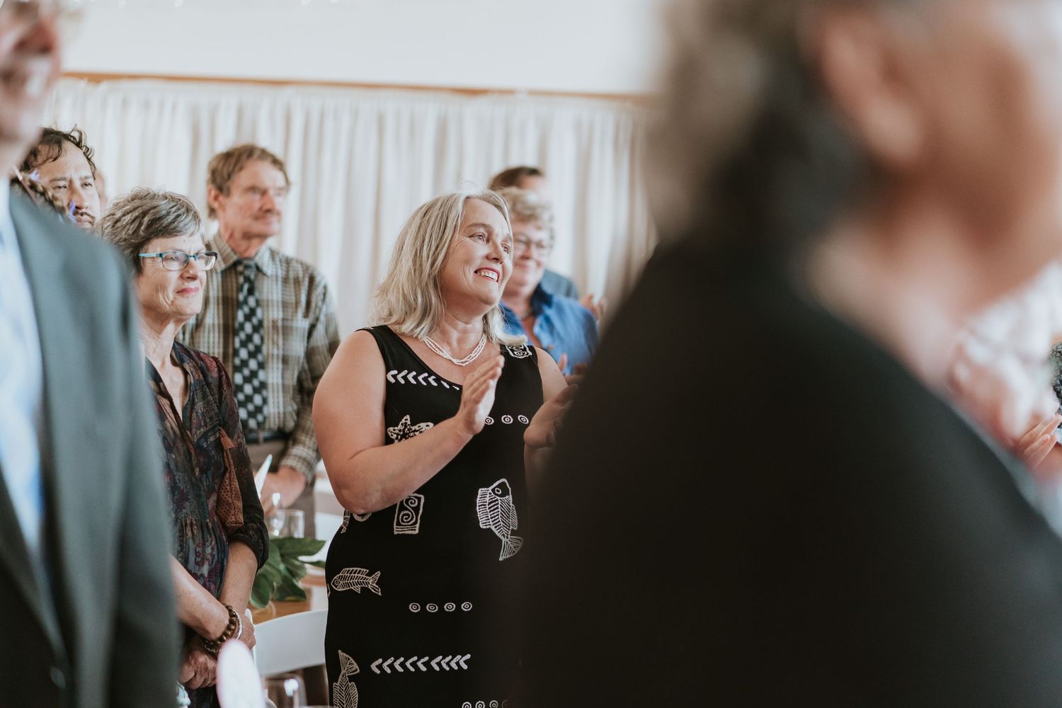 Wedding guests seated at tables react emotionally during a candid dining moment at the reception celebration.