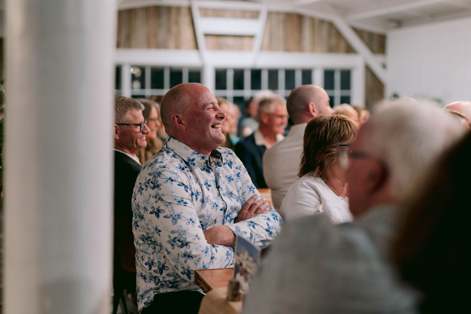 Guests enjoying themselves at a lively wedding reception in an indoor venue with white decor.