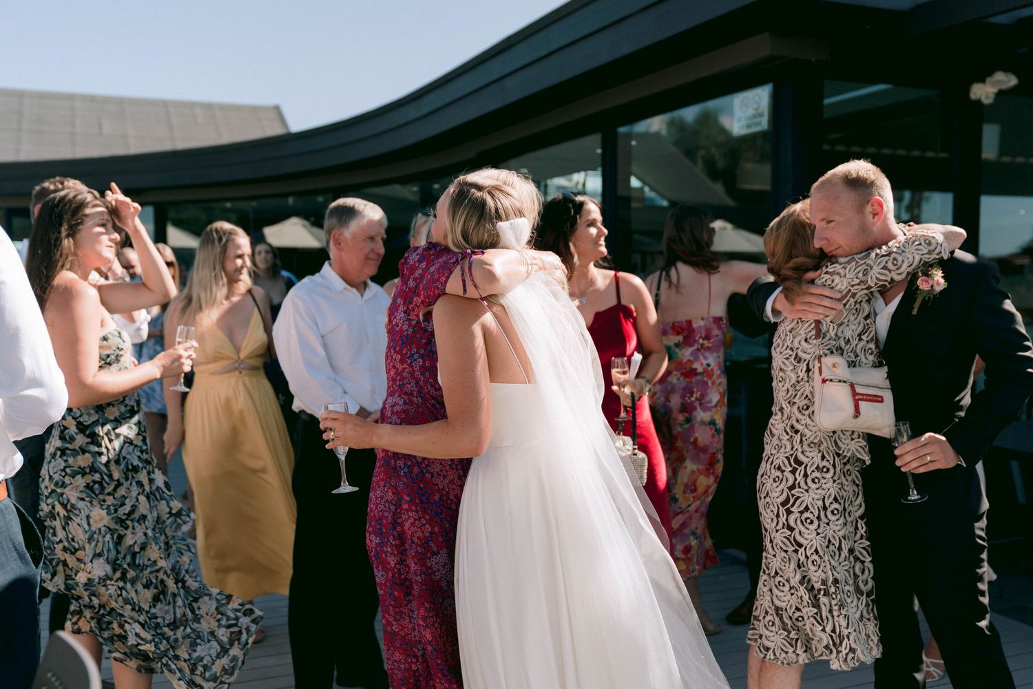 Wedding guests enjoying a lively celebration at an outdoor reception venue, dancing and mingling under open skies.