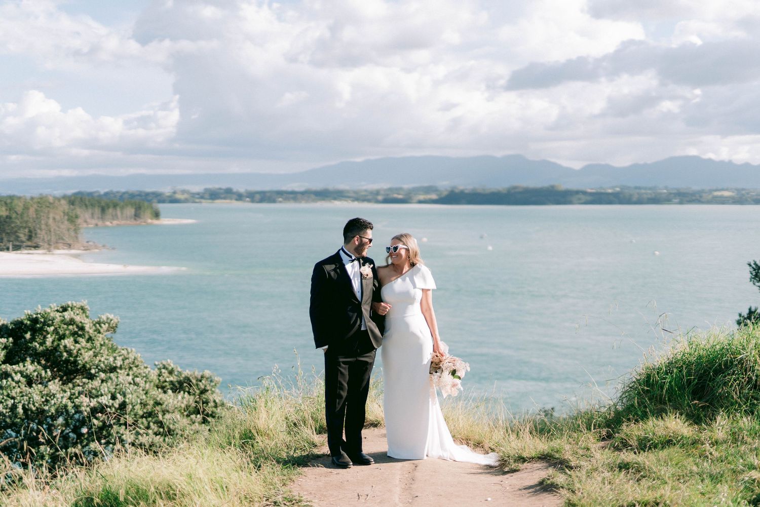Scenic coastal wedding portrait with mountains and bay in the background.