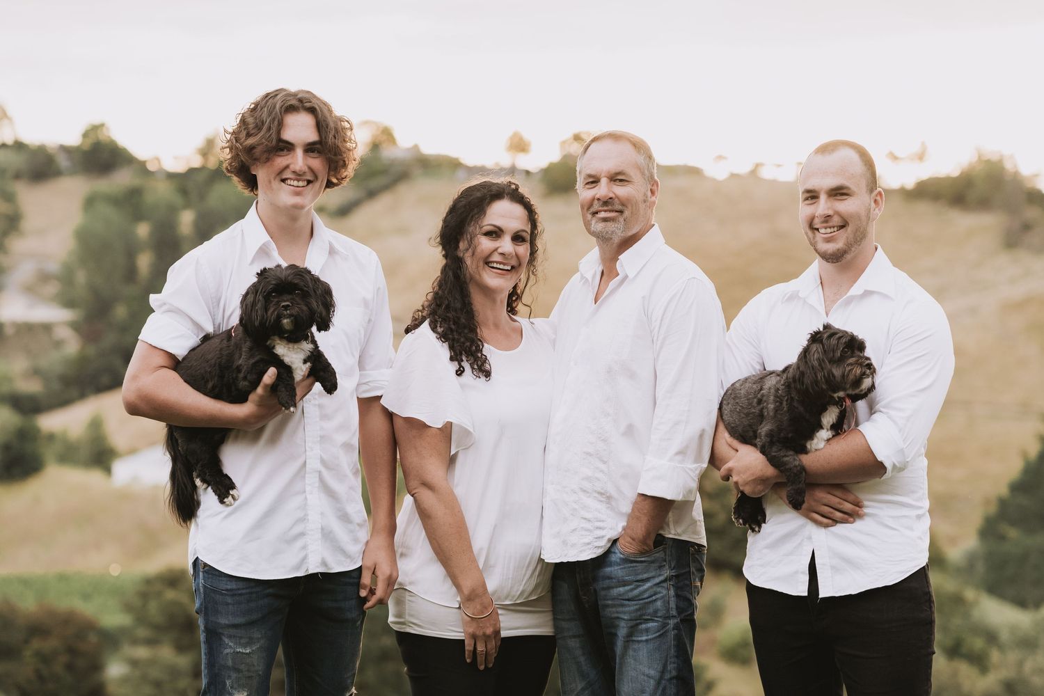 A happy family enjoys a candid moment together outdoors against a natural backdrop during a photography session.
