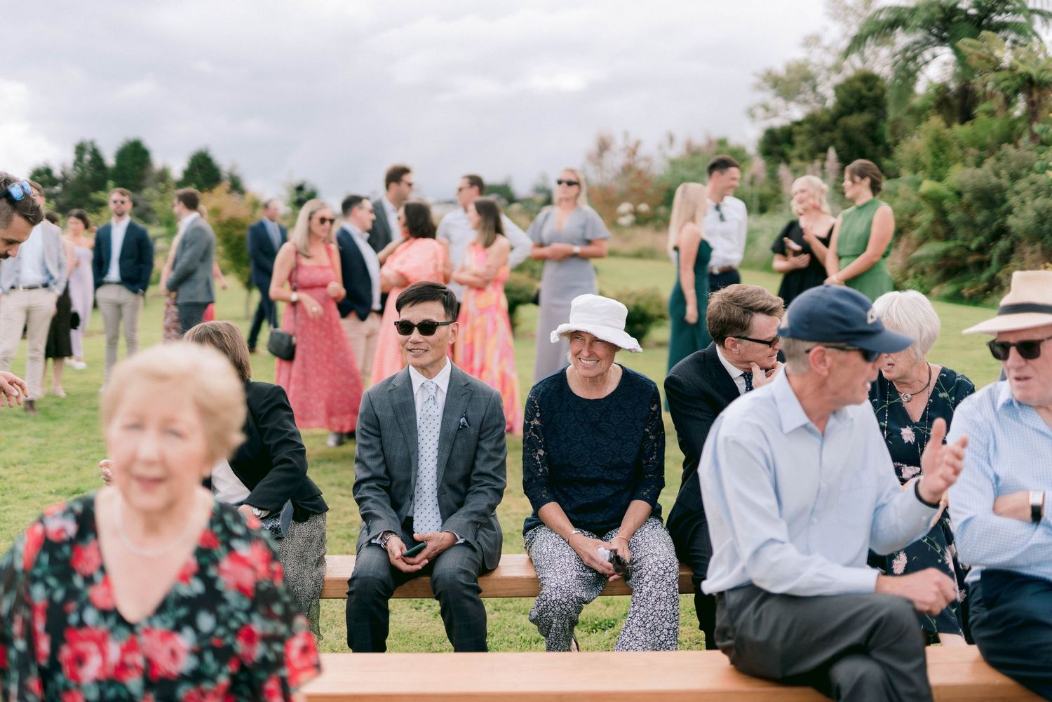Wedding guests enjoy outdoor cocktail hour on a sunny day at an elegant garden reception.