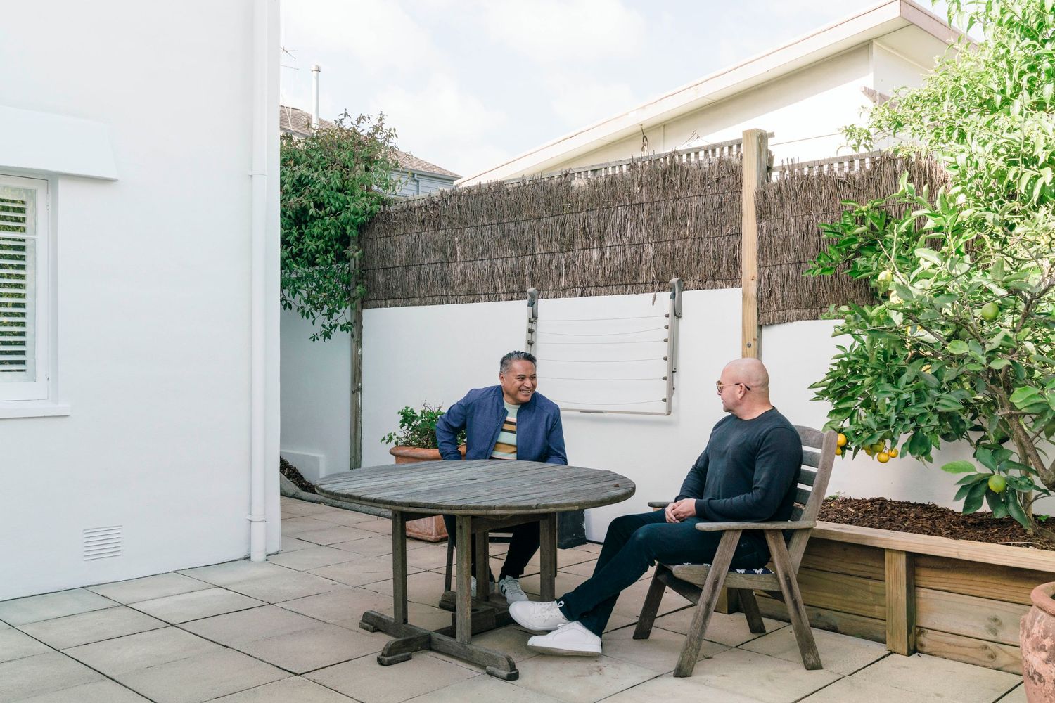 Outdoor patio seating area with bamboo privacy screen and potted plants.