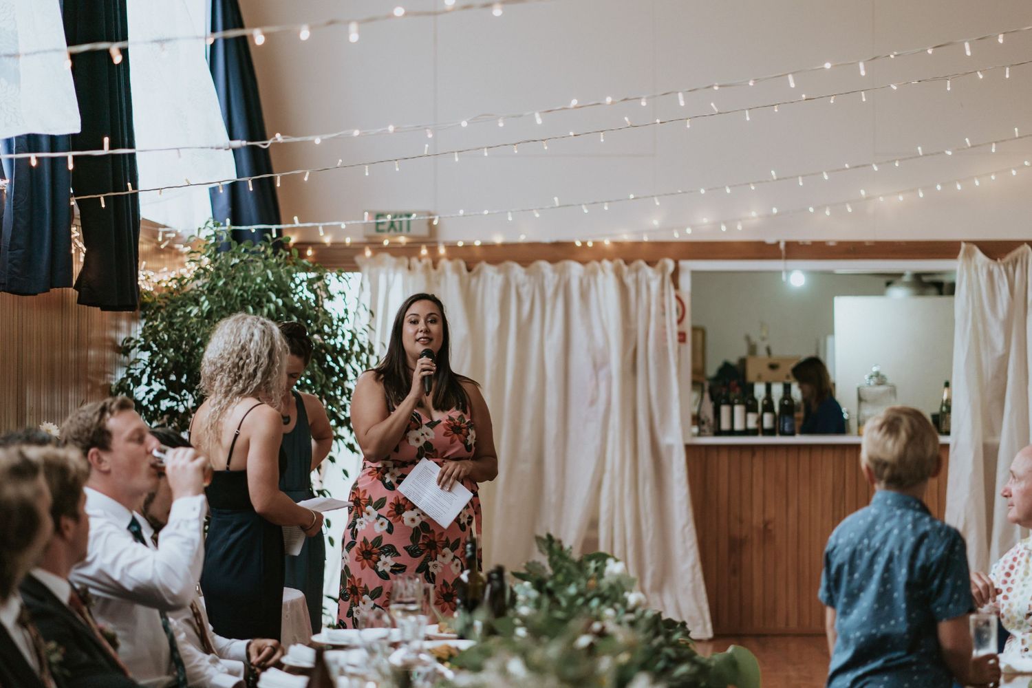 A reception celebration with twinkle lights and greenery decorations in an indoor venue.