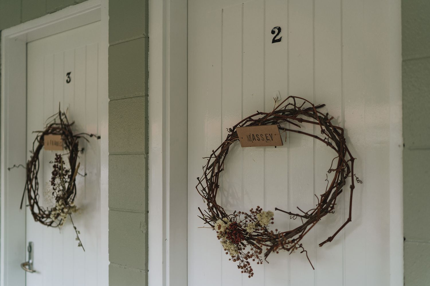 Rustic grapevine wreath decorations hanging on white wooden planked wall in farmhouse style.