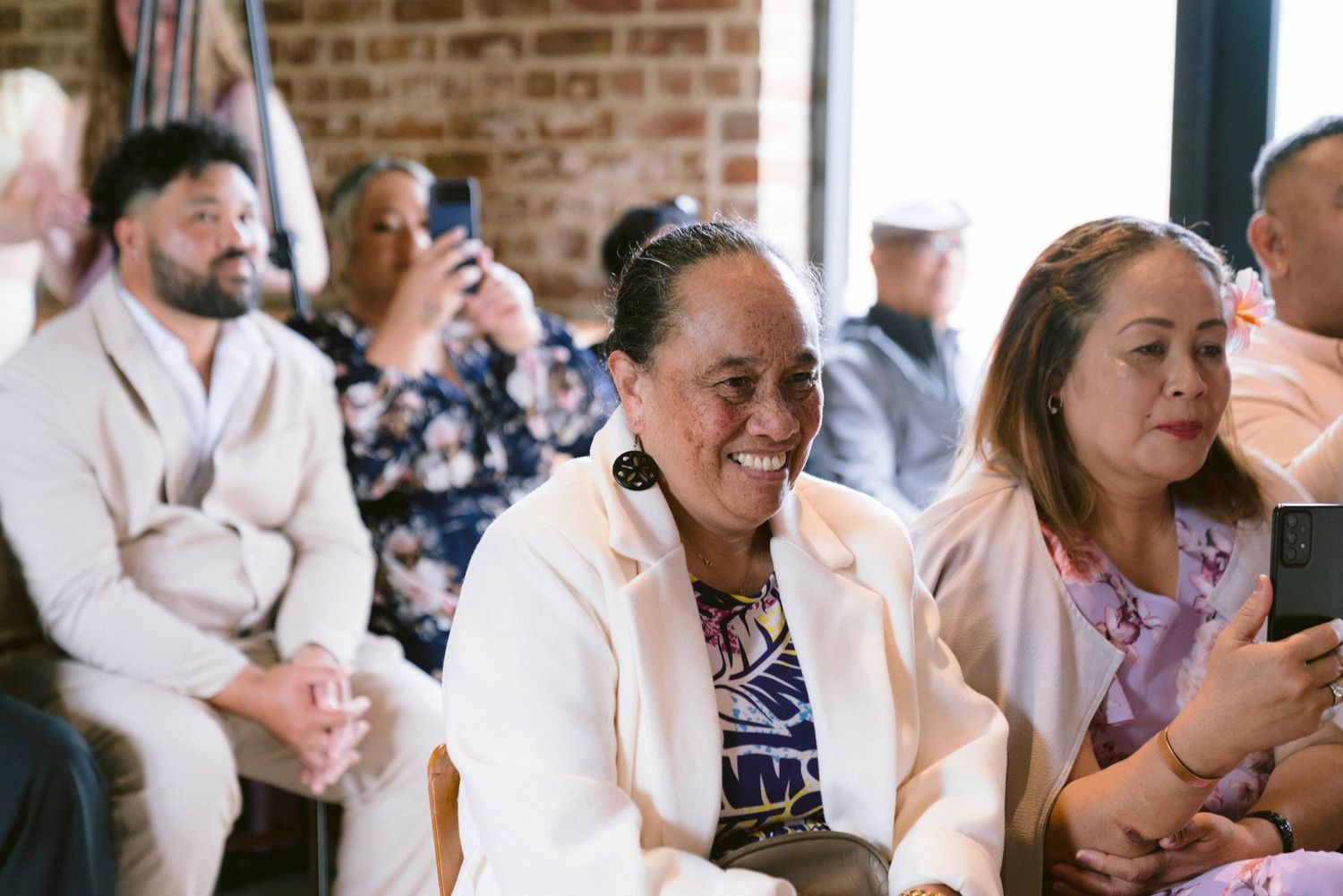 Wedding guests laughing and celebrating during reception in a rustic brick venue.