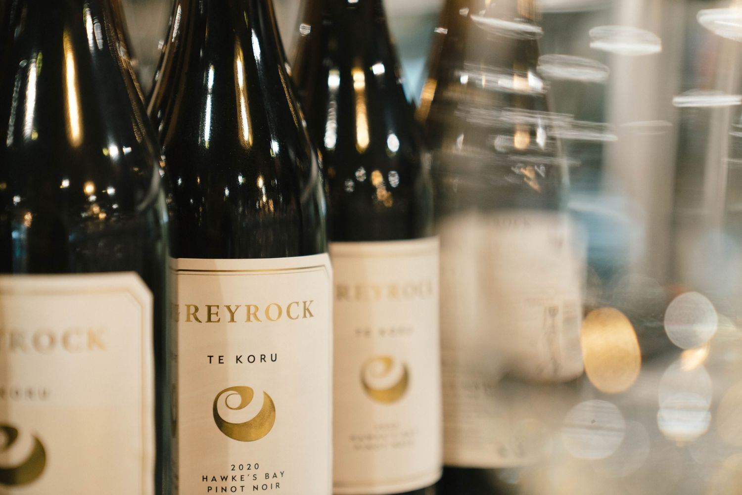Wine bottles from Reyrock winery arranged on display with soft bokeh lighting in the background.