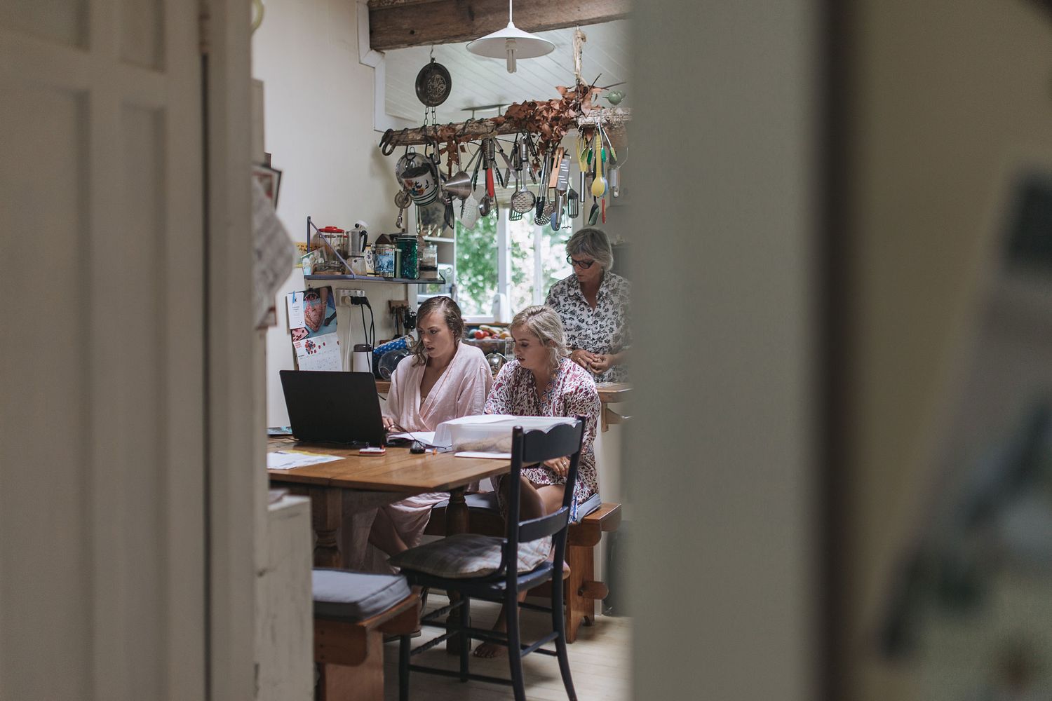 Two people sitting at a dining table in a rustic home with natural light streaming through the windows.