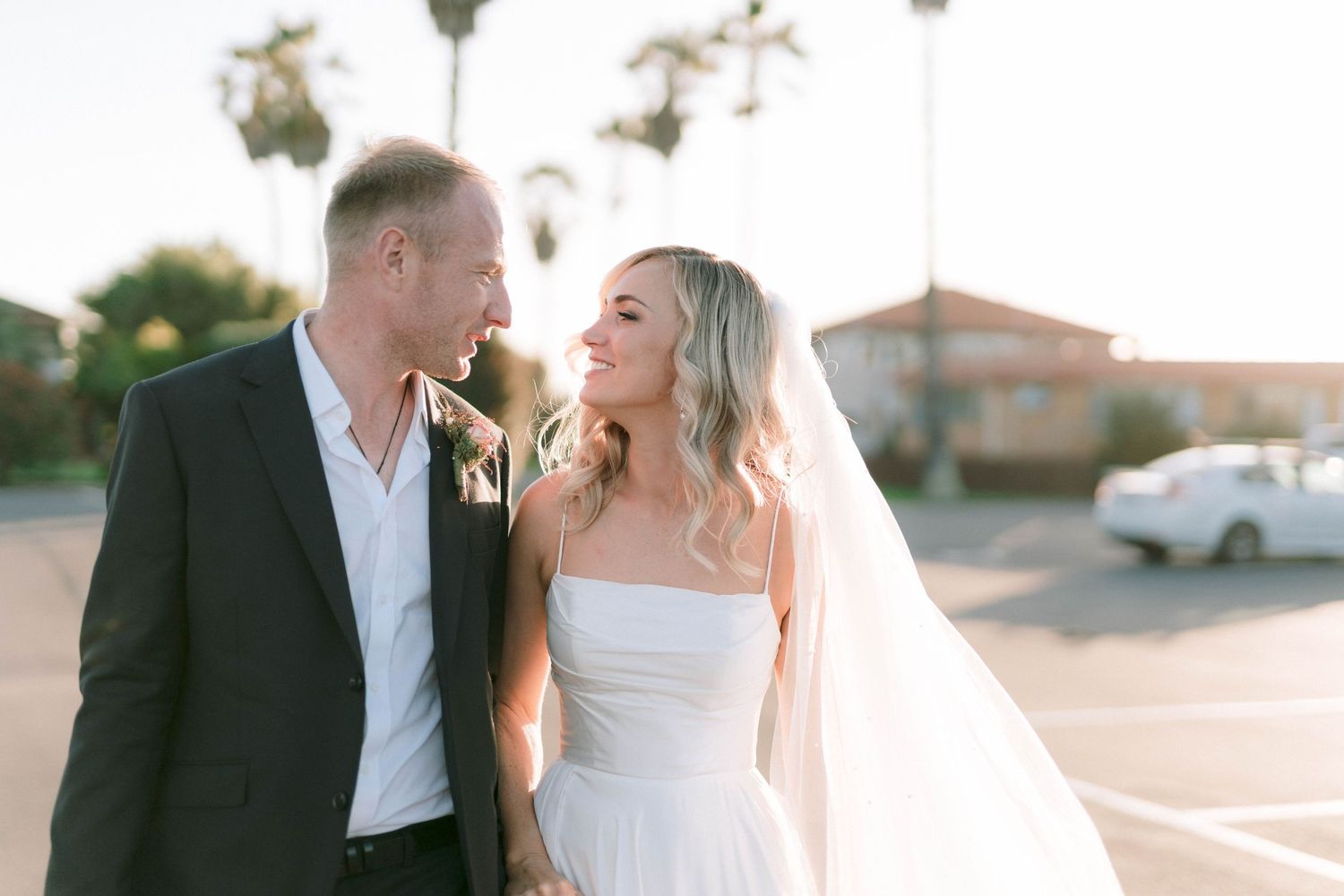Newlyweds share romantic moments during golden hour with palm trees in background.