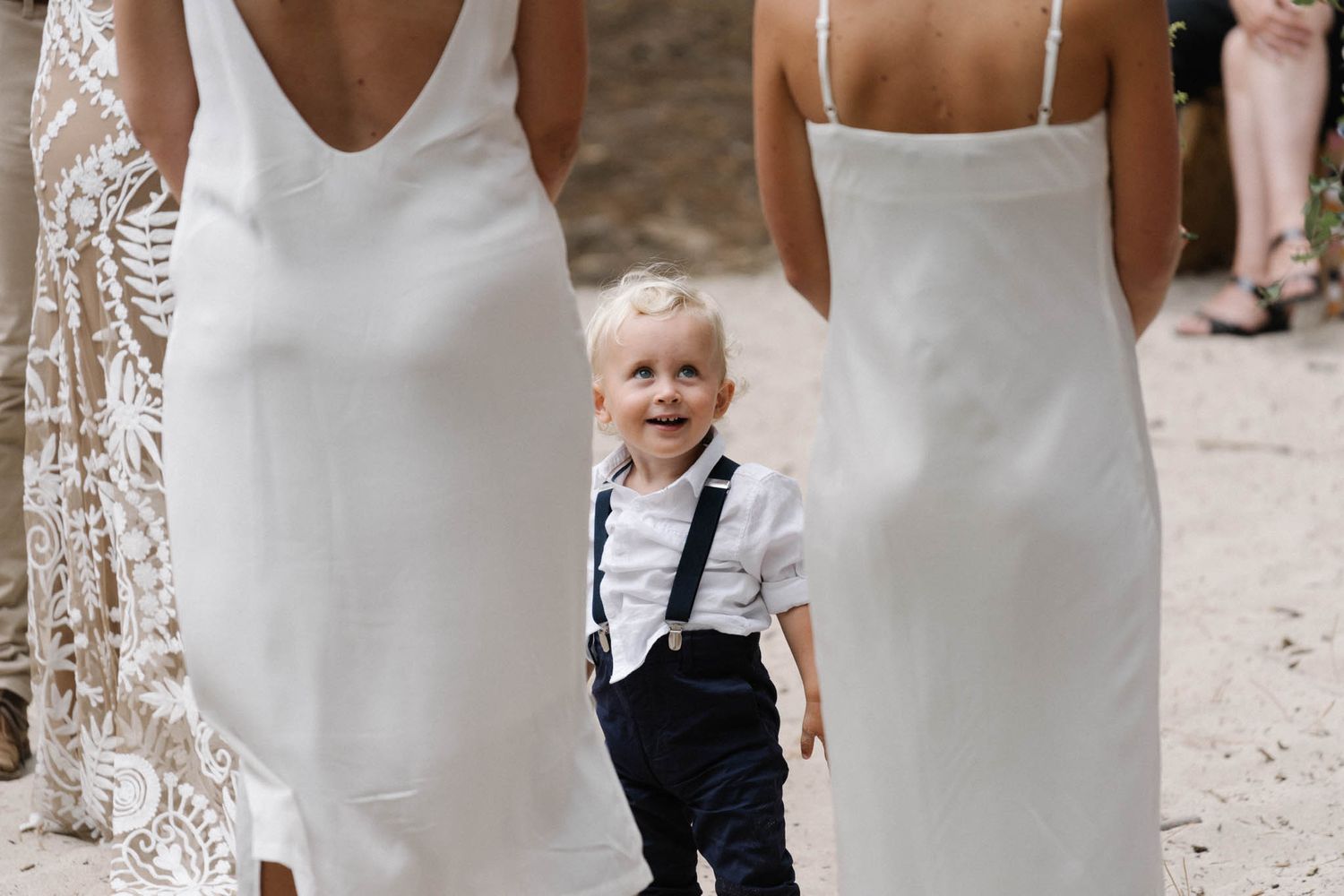 Elegant lace wedding dress with flowing train swaying in gentle breeze during outdoor photo session.