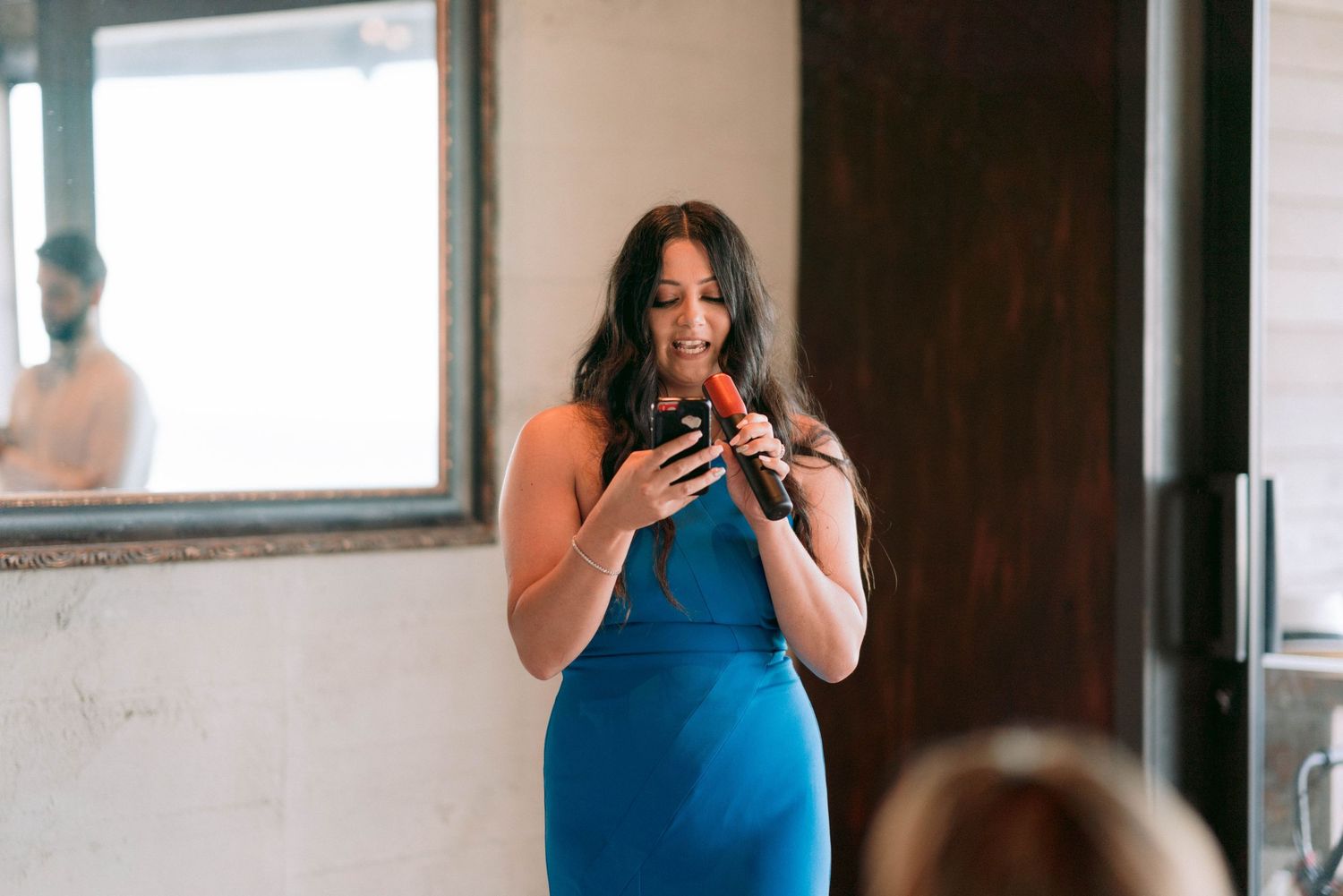 Wedding guests take photos on their phones during an indoor reception.