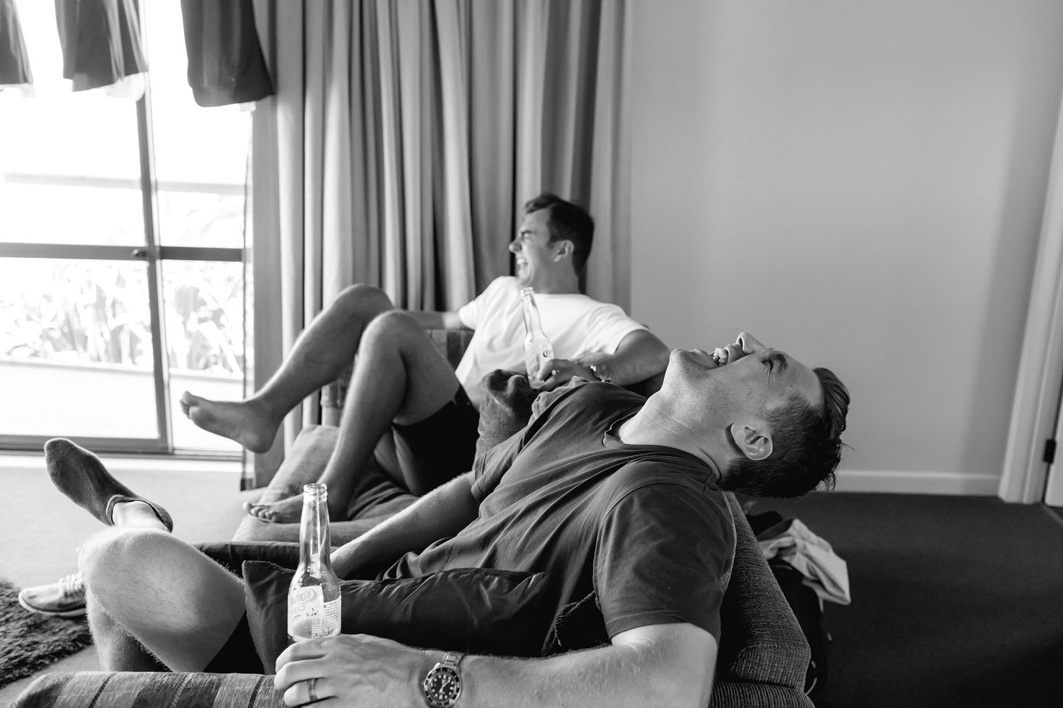 Two people relax together on furniture while wearing casual clothes in a black and white photograph.