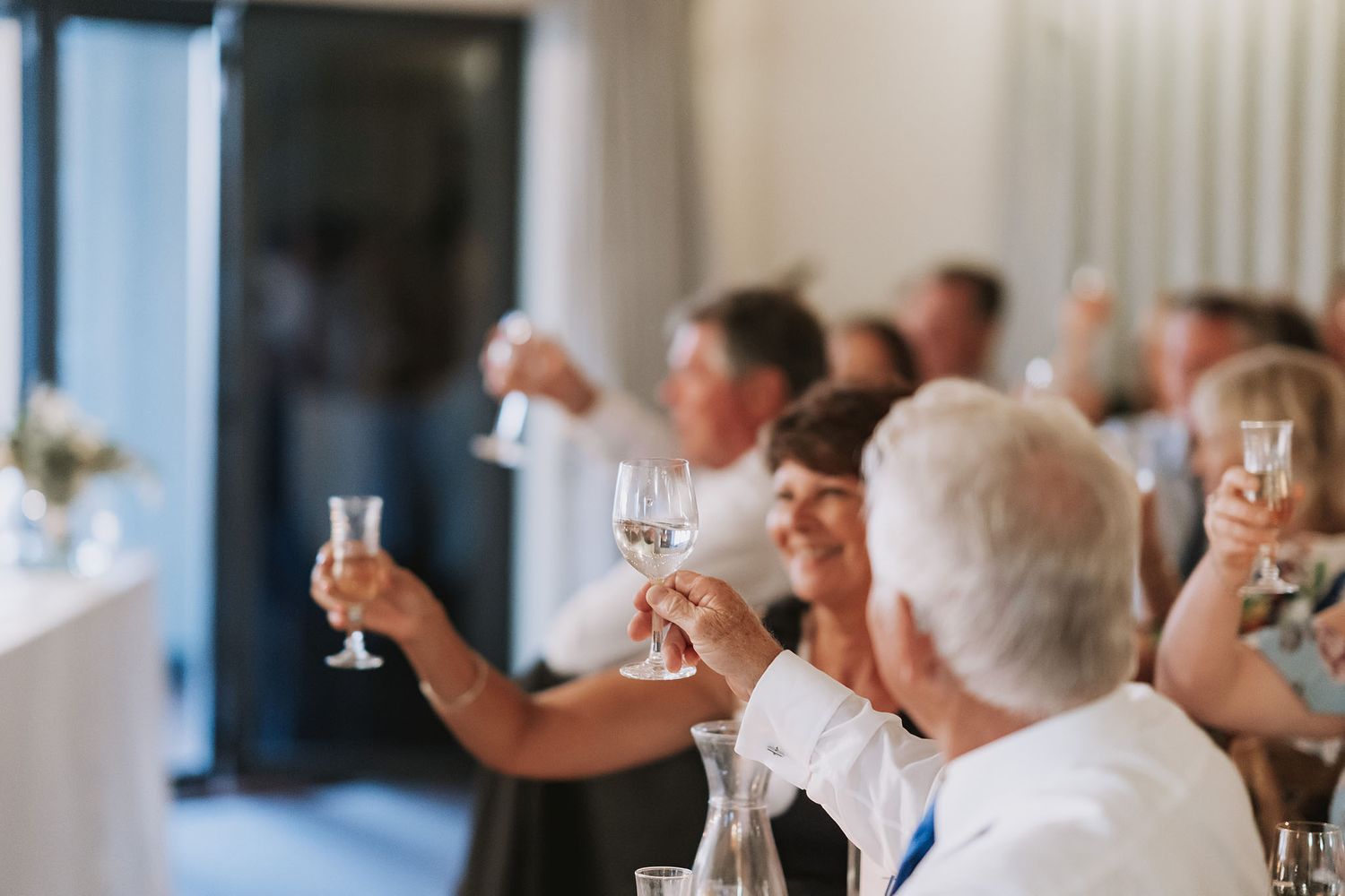 People enjoying drinks and conversation during an elegant social gathering in a bright, minimalist venue.