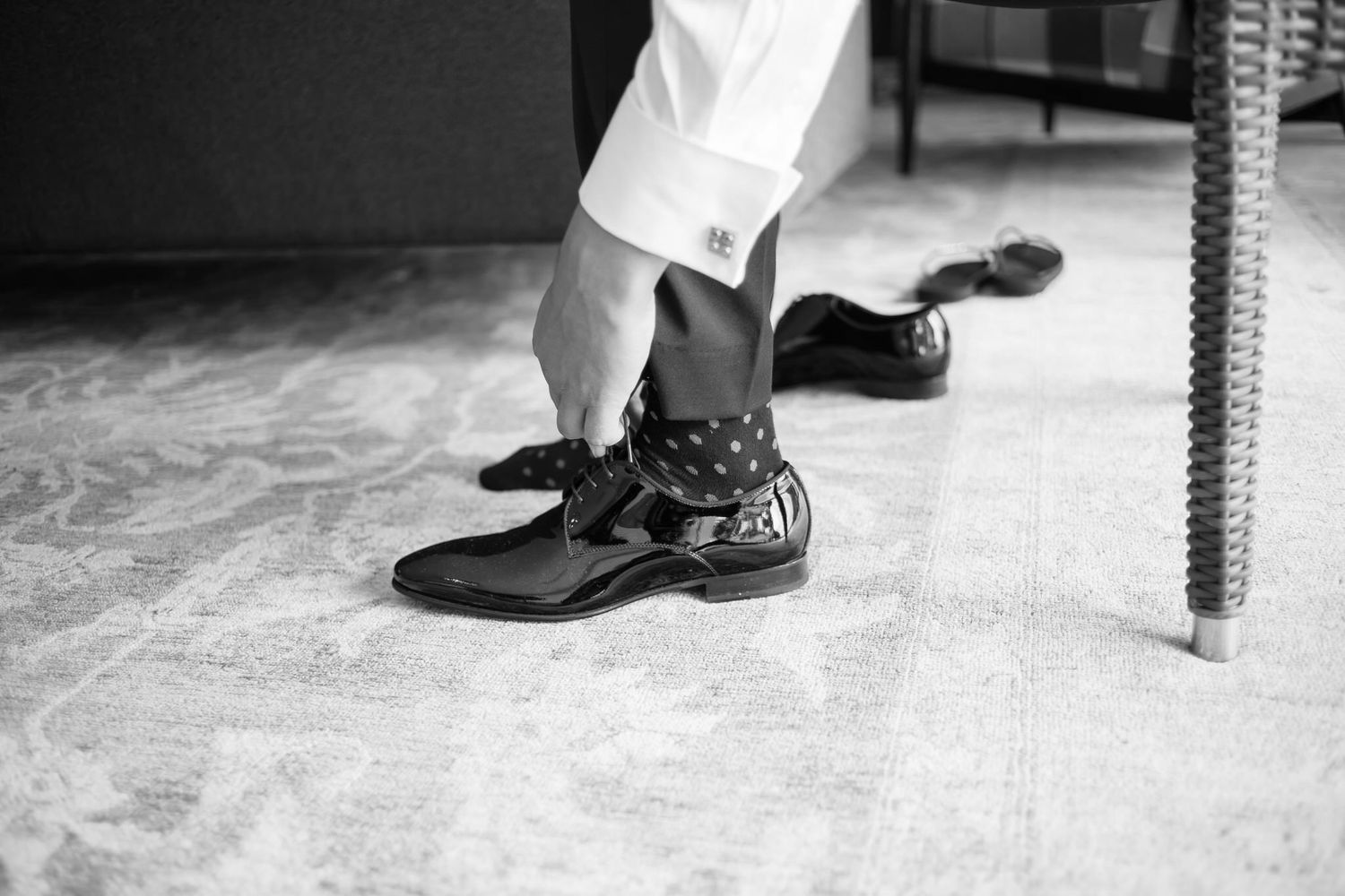 Black and white close-up of feet wearing tap shoes and dress shoes resting on a hardwood floor.