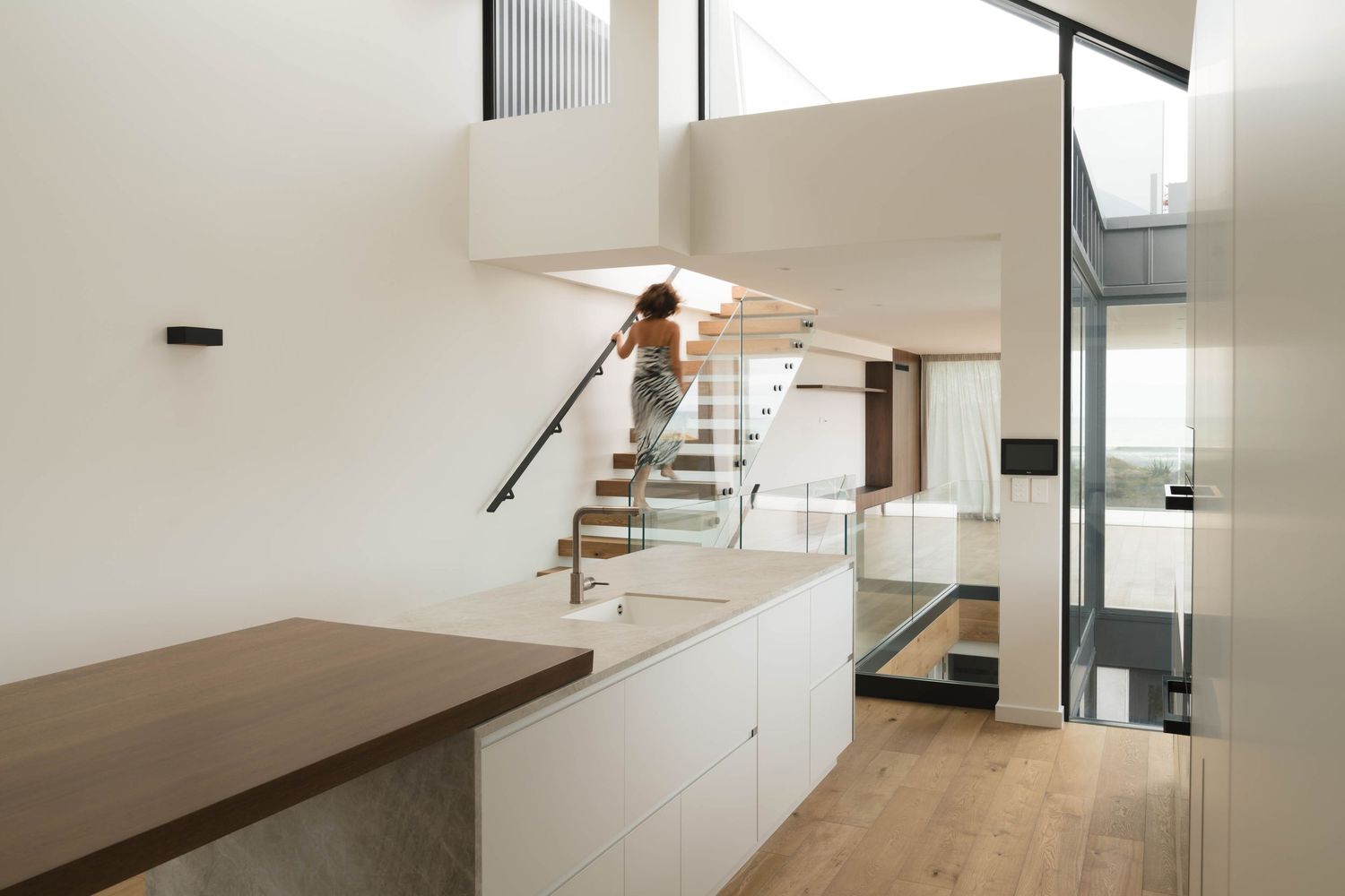 Minimalist white interior hallway with modern stairs and natural lighting.