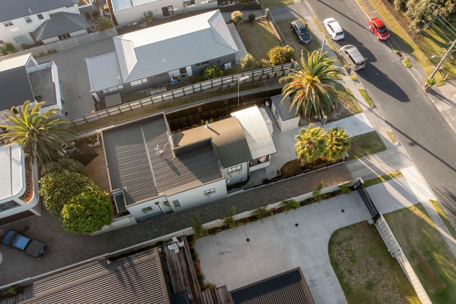 Aerial view of modern buildings with palm trees and parking area on sunny day.
