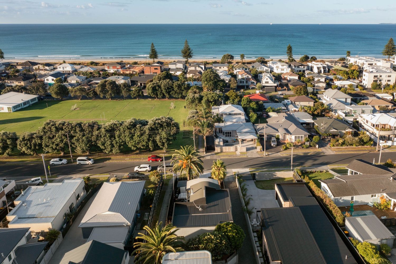 Aerial view of a coastal residential neighborhood with palm trees and beach access in Australia.