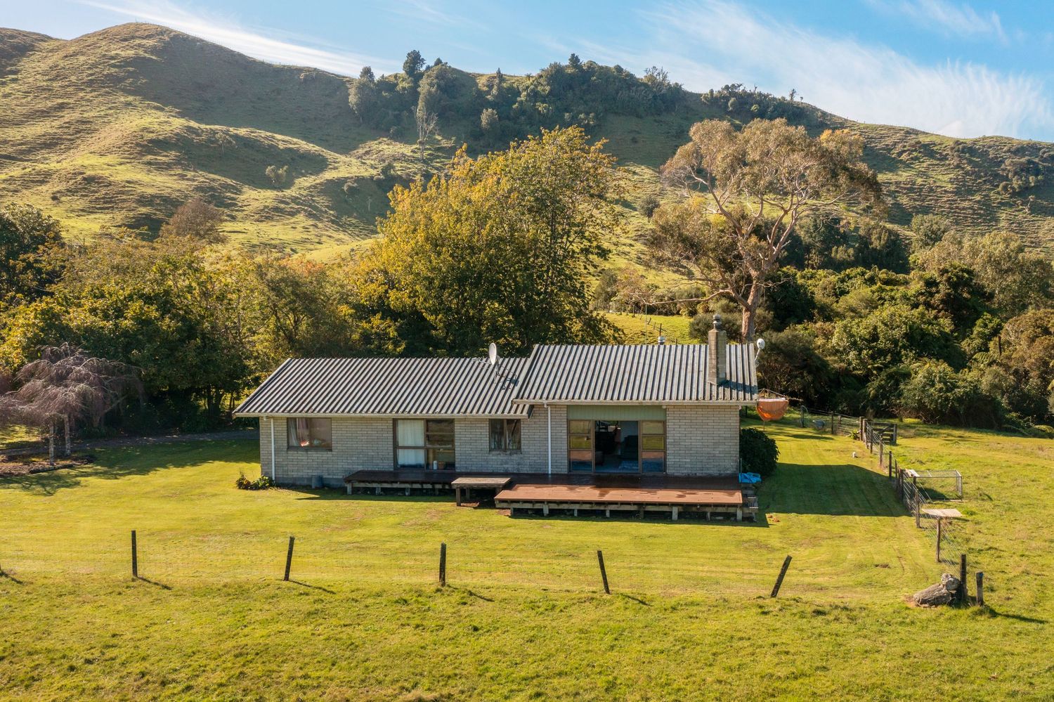 Panoramic view of a rural mountain property with scattered trailers and buildings nestled among rolling green hills.