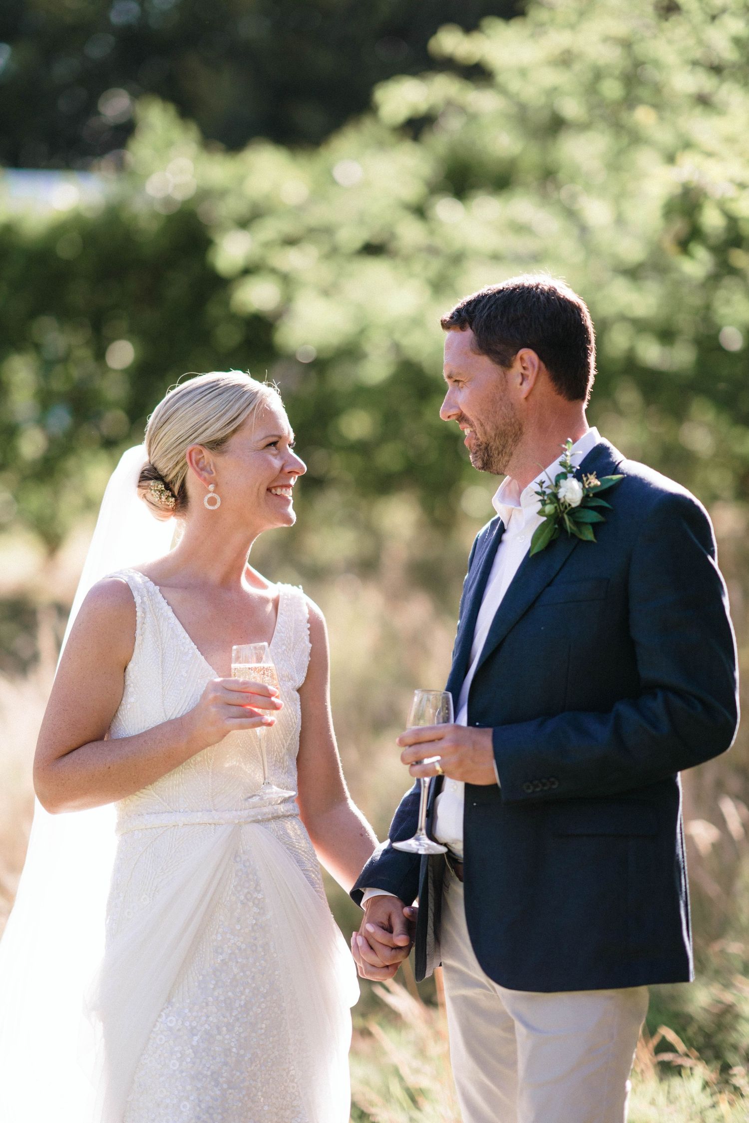 Wedding couple shares champagne and laughter during outdoor portrait session.