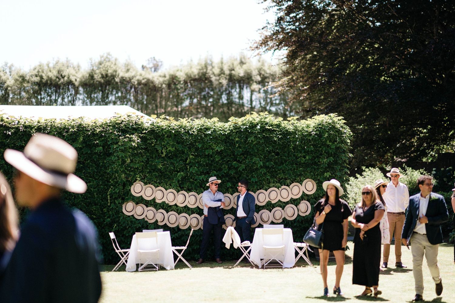 Outdoor wedding reception setup with hanging decorative bunting banners and green foliage in background.