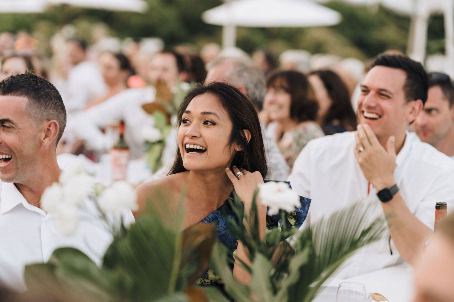 Wedding guests enjoying candid moments during outdoor reception with tropical decor.