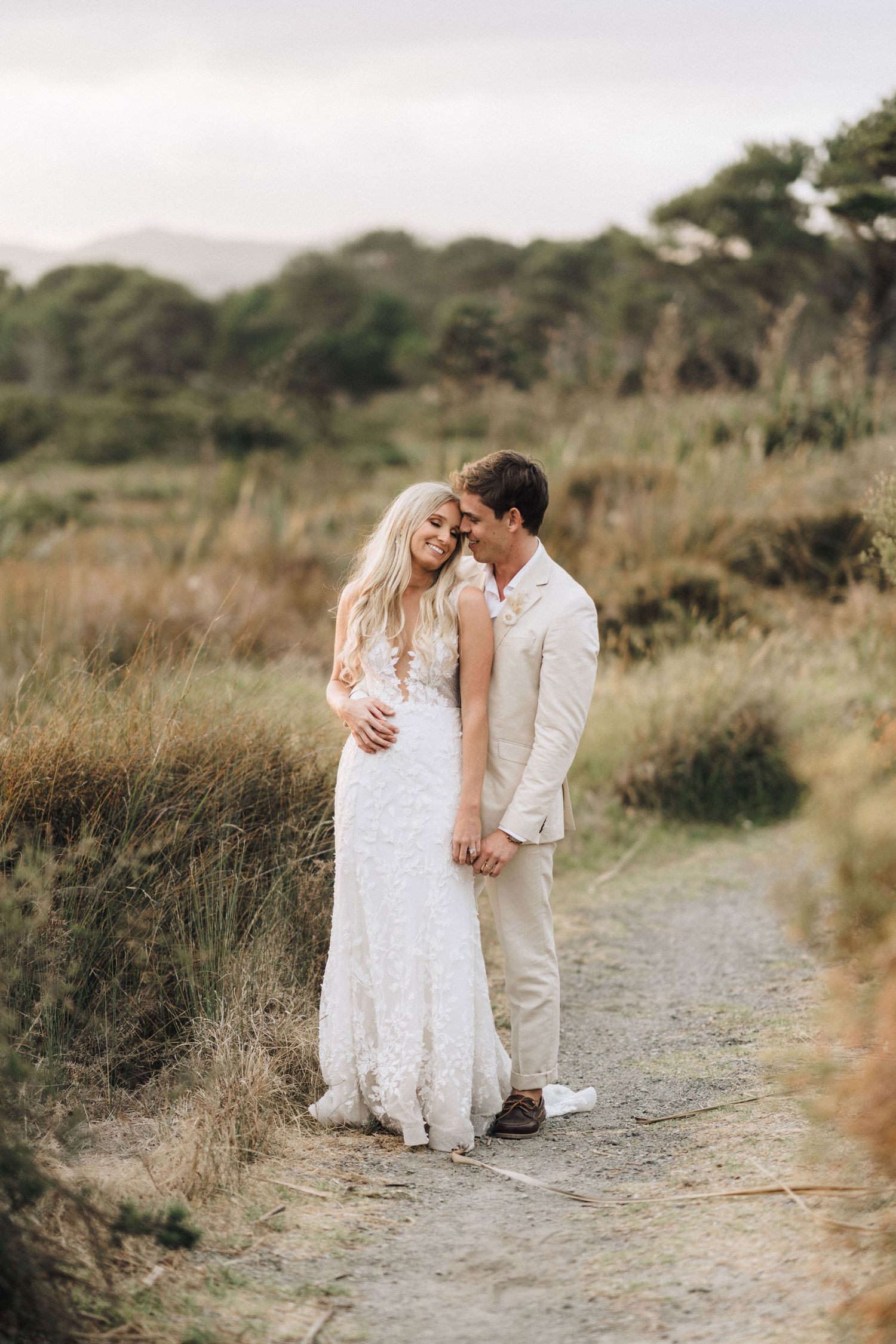 Romantic moment between newlyweds on a nature path surrounded by coastal vegetation.