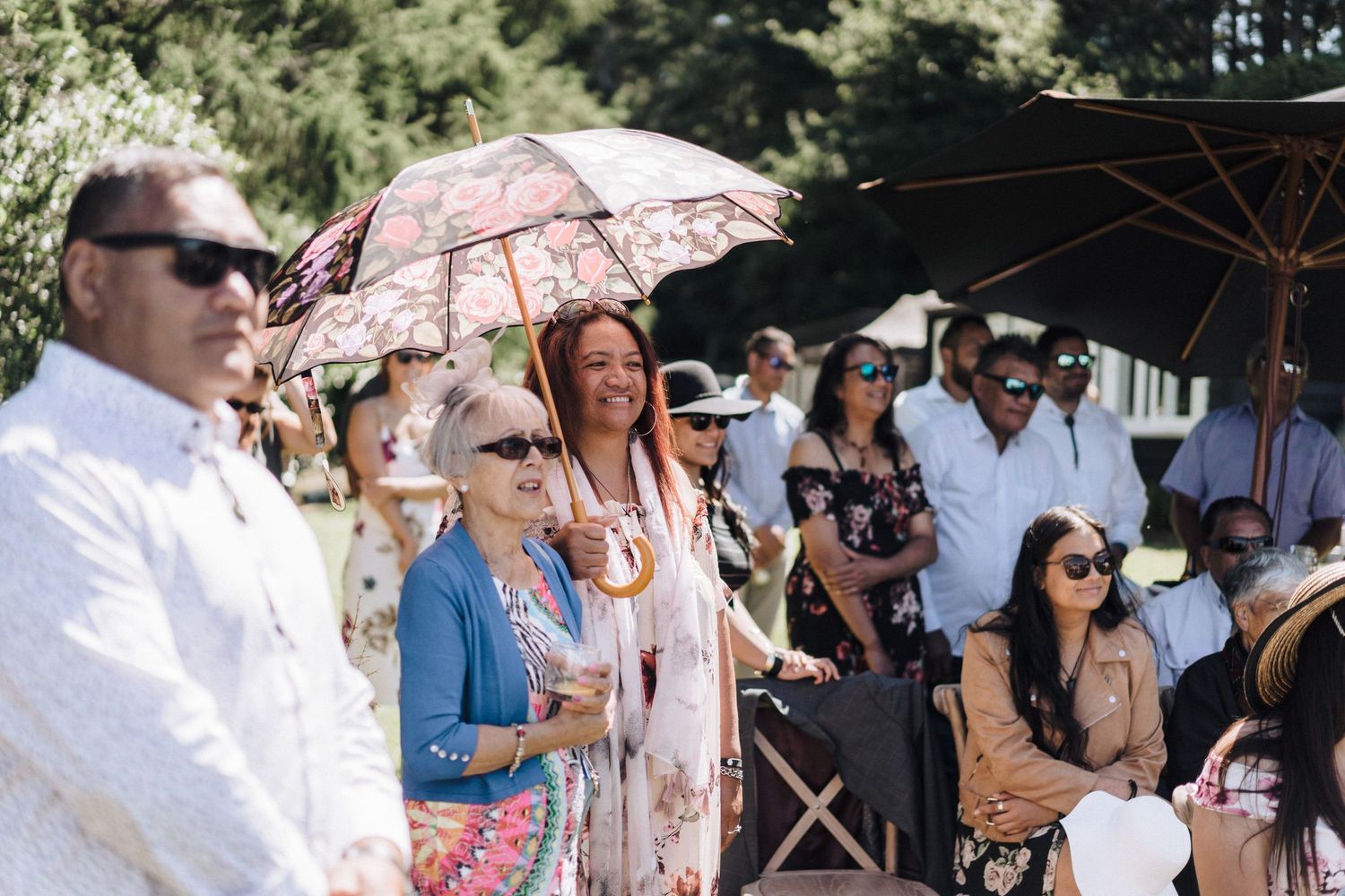 Wedding guests enjoy an outdoor celebration with decorative parasols.
