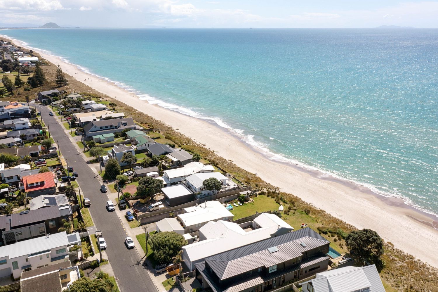 Aerial view of beachfront homes along turquoise coastline with sandy beach and residential street in Florida.