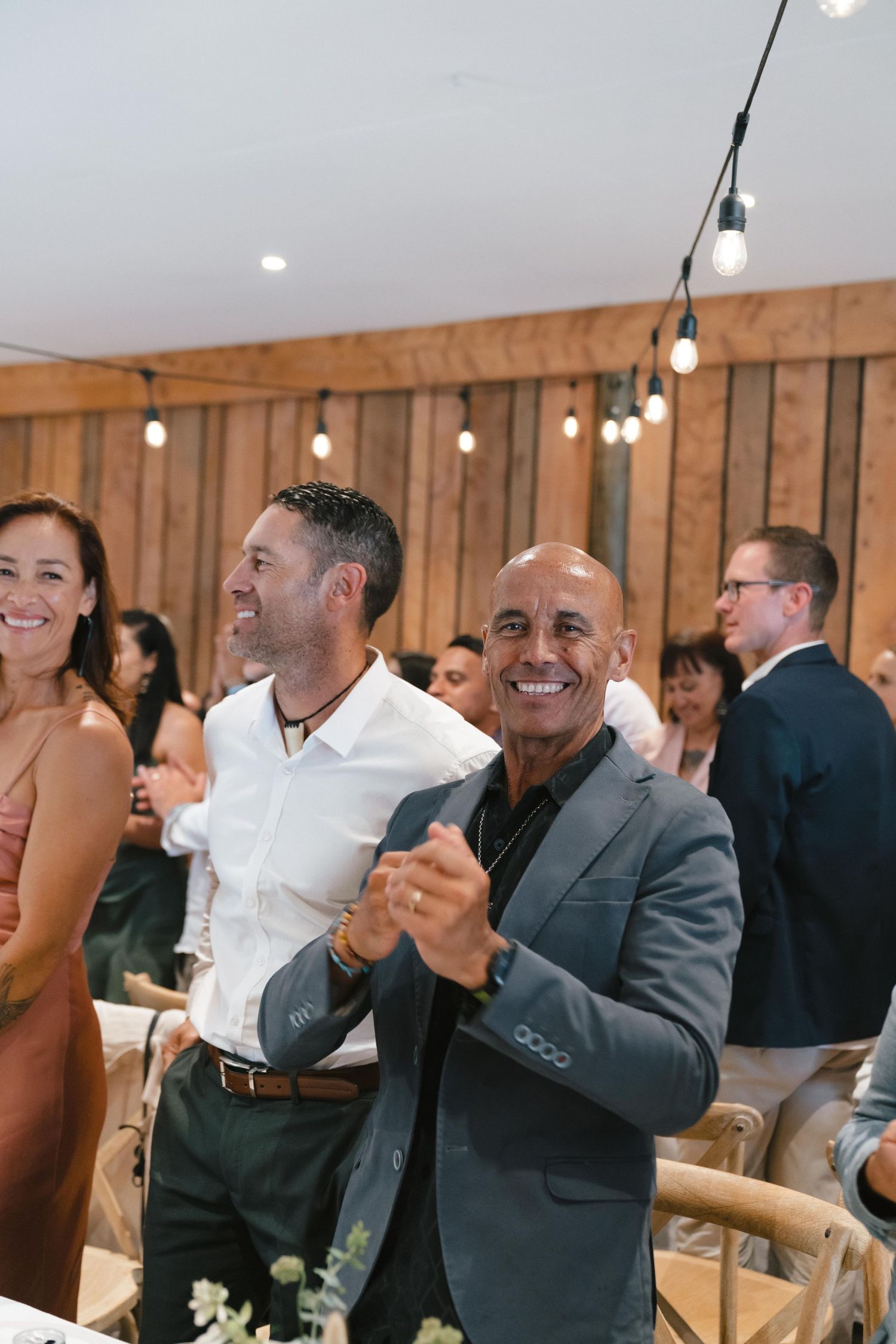 Wedding guests cheering and celebrating inside a modern barn reception venue.