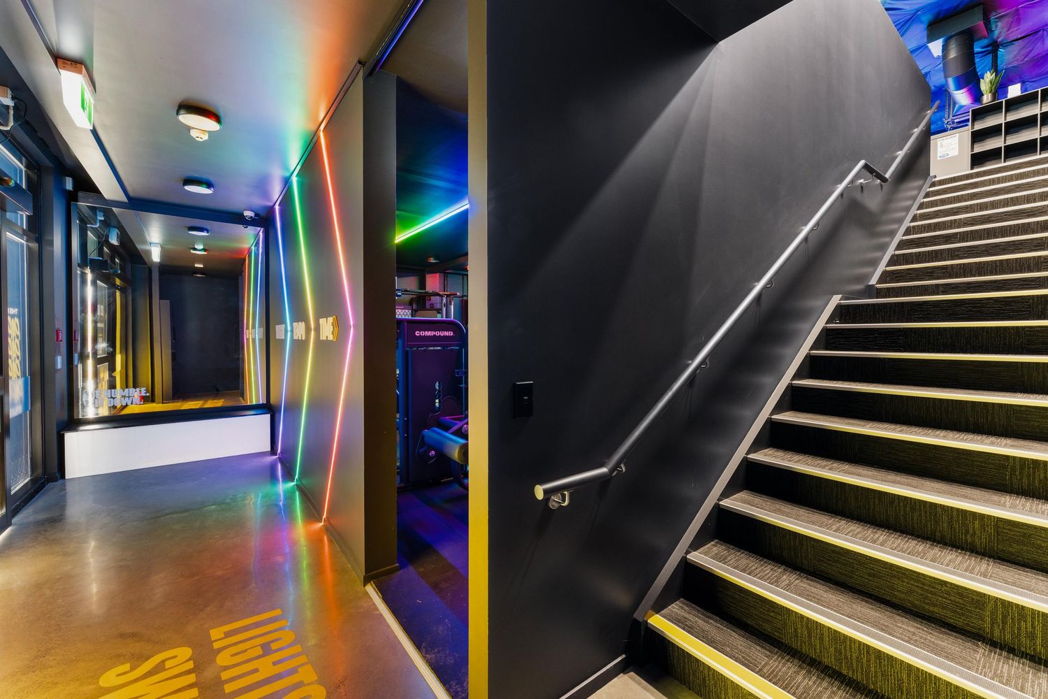 Modern gym hallway and staircase featuring geometric LED lighting designs and sleek architectural elements.