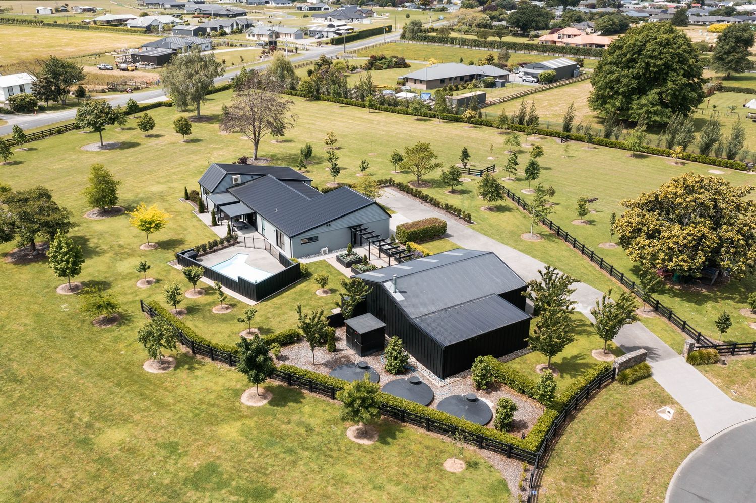 Aerial view of rural residential properties with large green yards and homes scattered across rolling countryside terrain.
