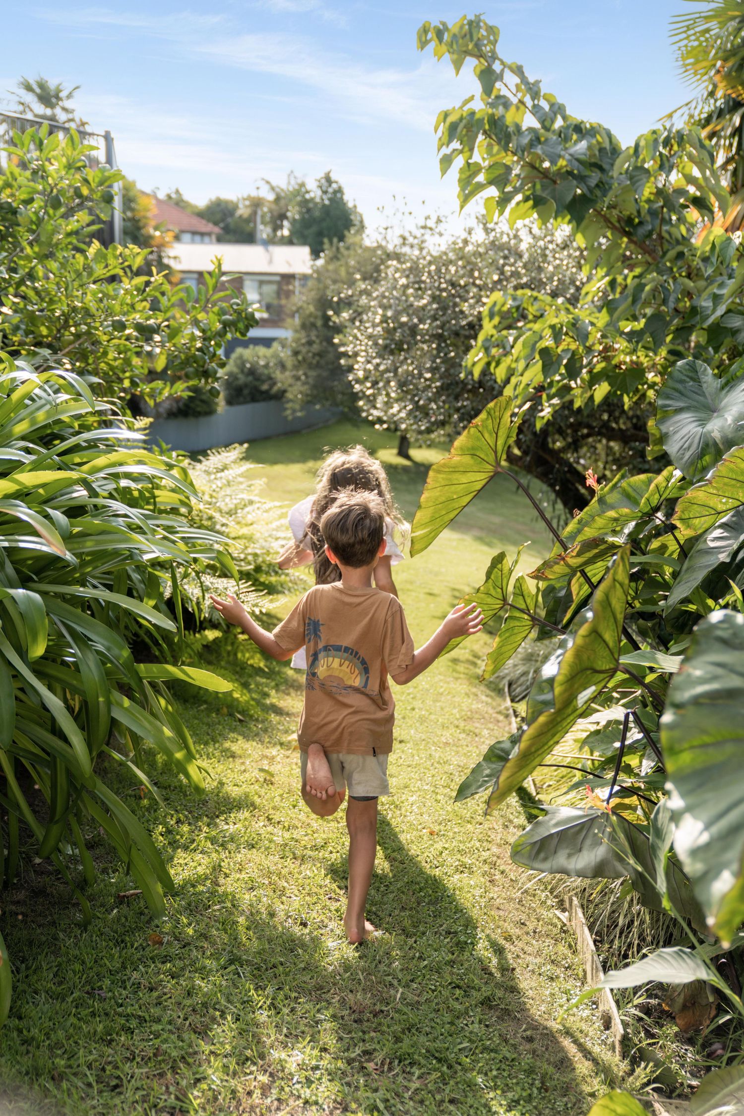 Young explorers walking through a garden path surrounded by tropical foliage.