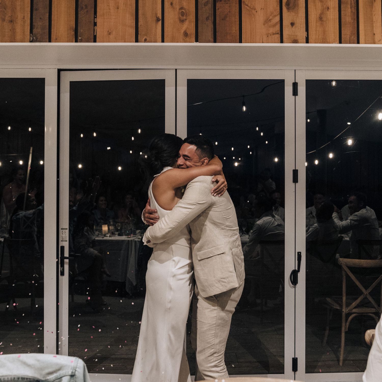 Large glass doors and walls create a modern reception space with twinkling lights visible at night.