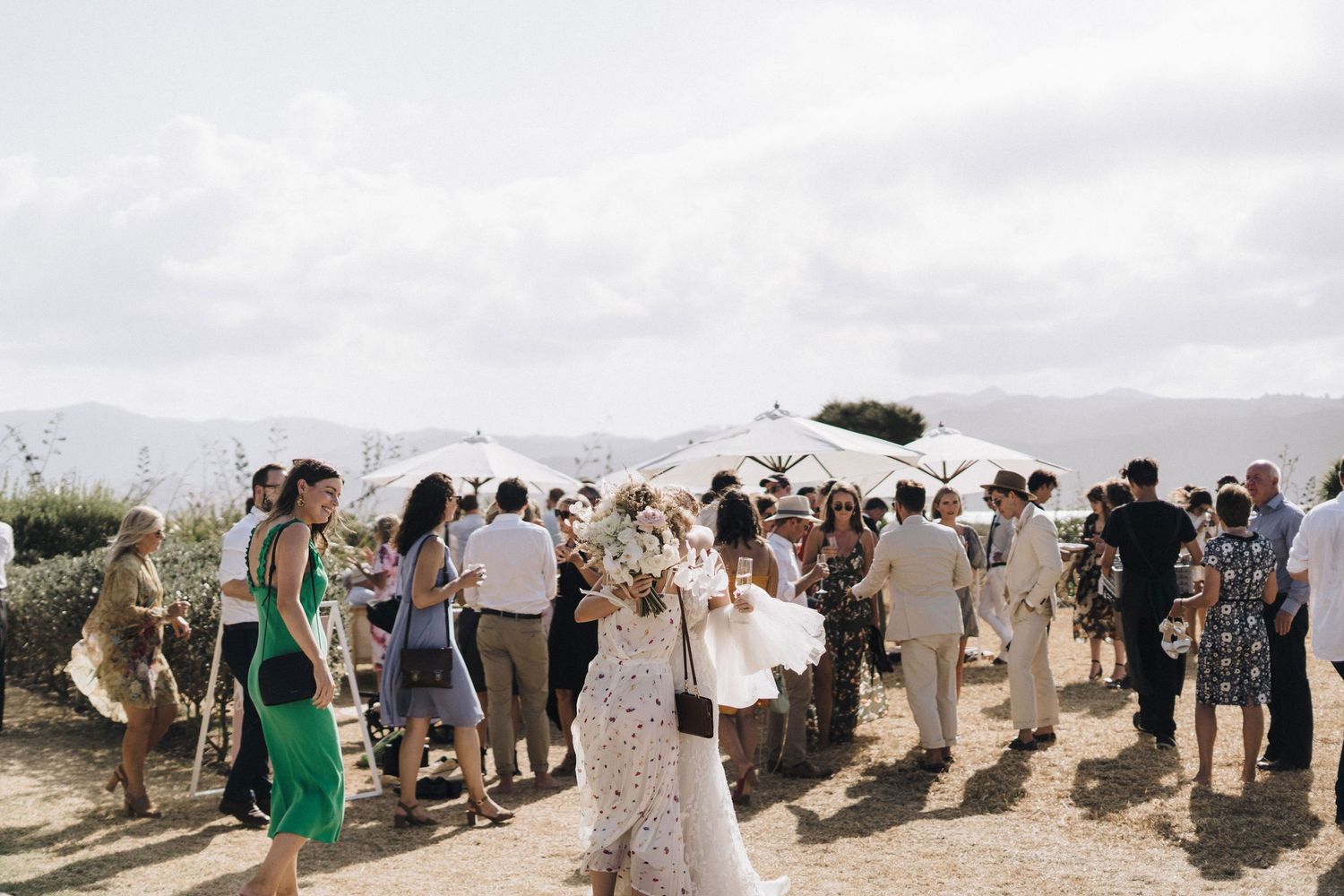 Outdoor wedding celebration with guests mingling under cloudy skies.