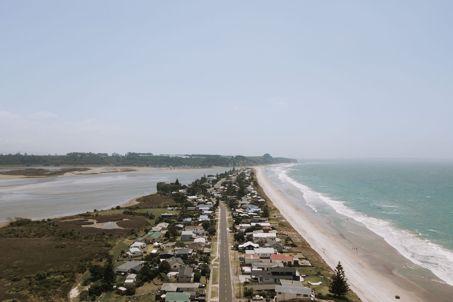 Panoramic aerial view of an ocean coastline with sandy beaches stretching along turquoise waters and coastal development.