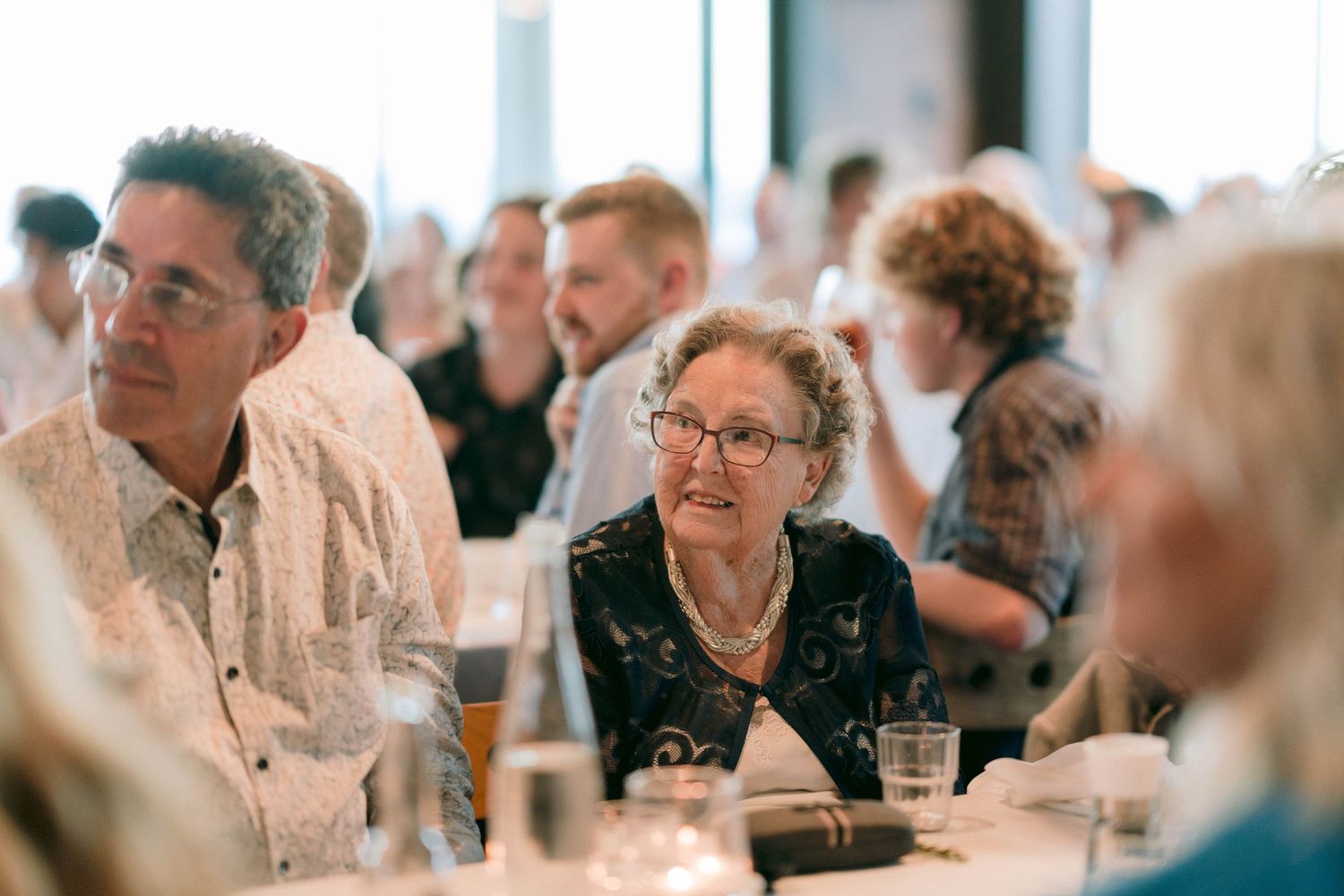 Wedding reception guests enjoying conversation and drinks at round tables.