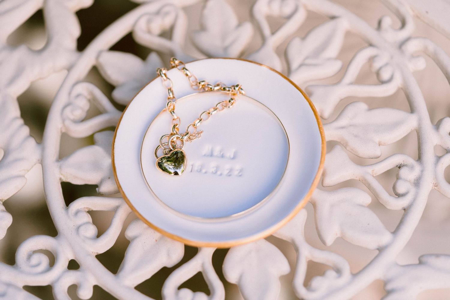 Gold ring and jewelry accessories displayed on delicate white lace in an elegant bridal styled arrangement.