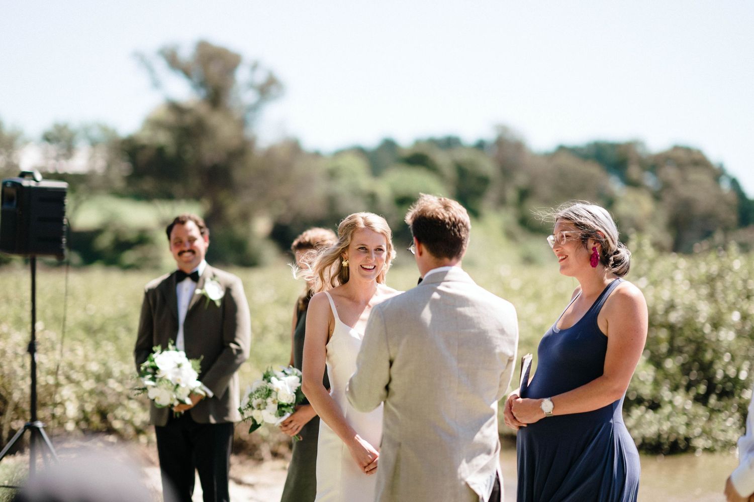 Outdoor wedding ceremony setting by the waterfront with guests in formal attire.