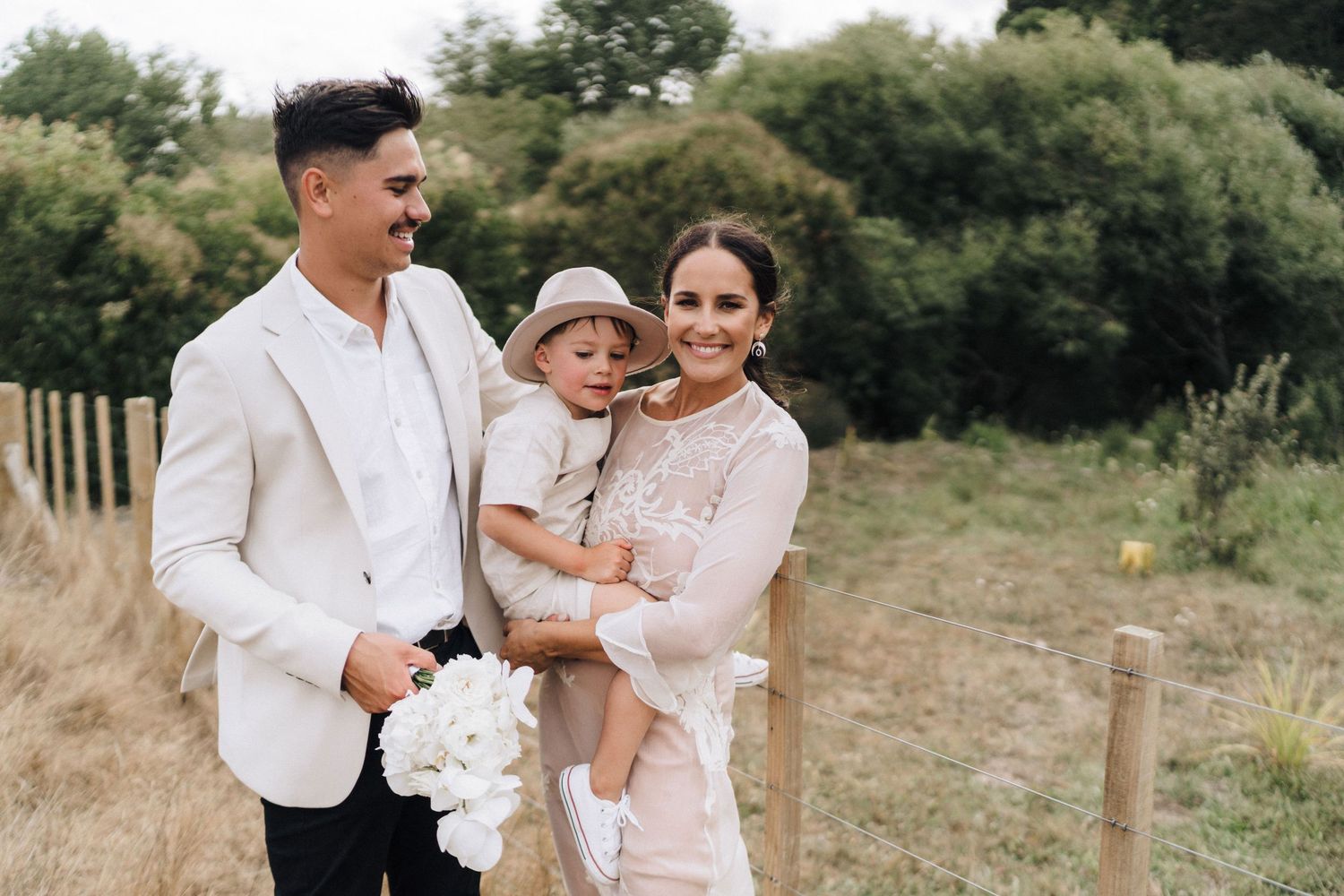 Family in coordinated white and beige outfits standing in outdoor setting.