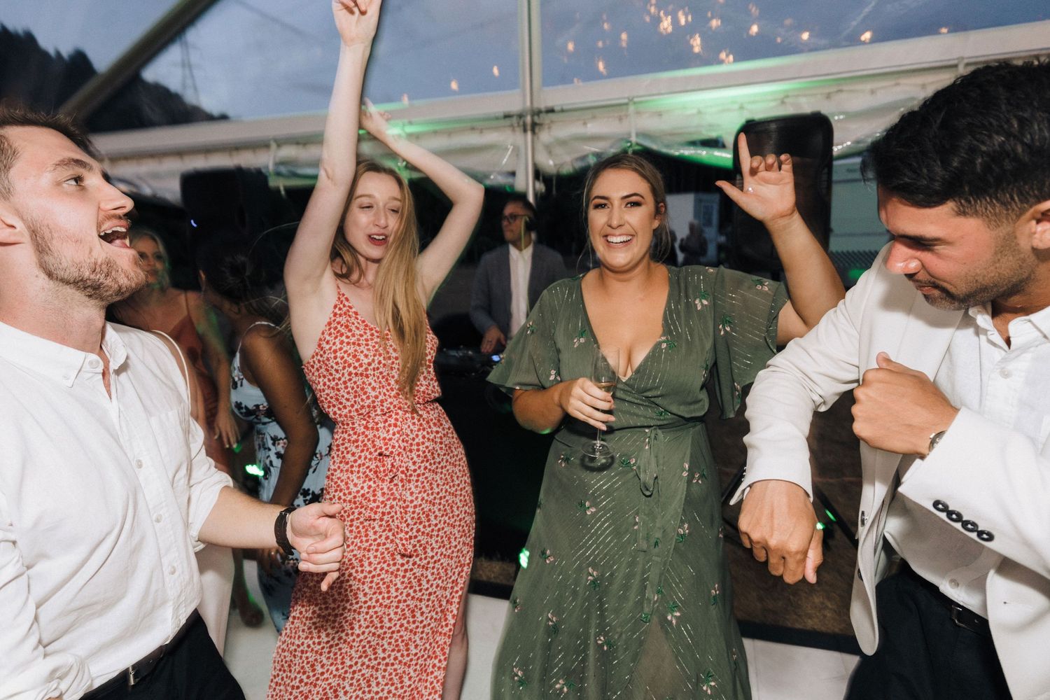 Group of party guests dancing under string lights at an outdoor celebration.