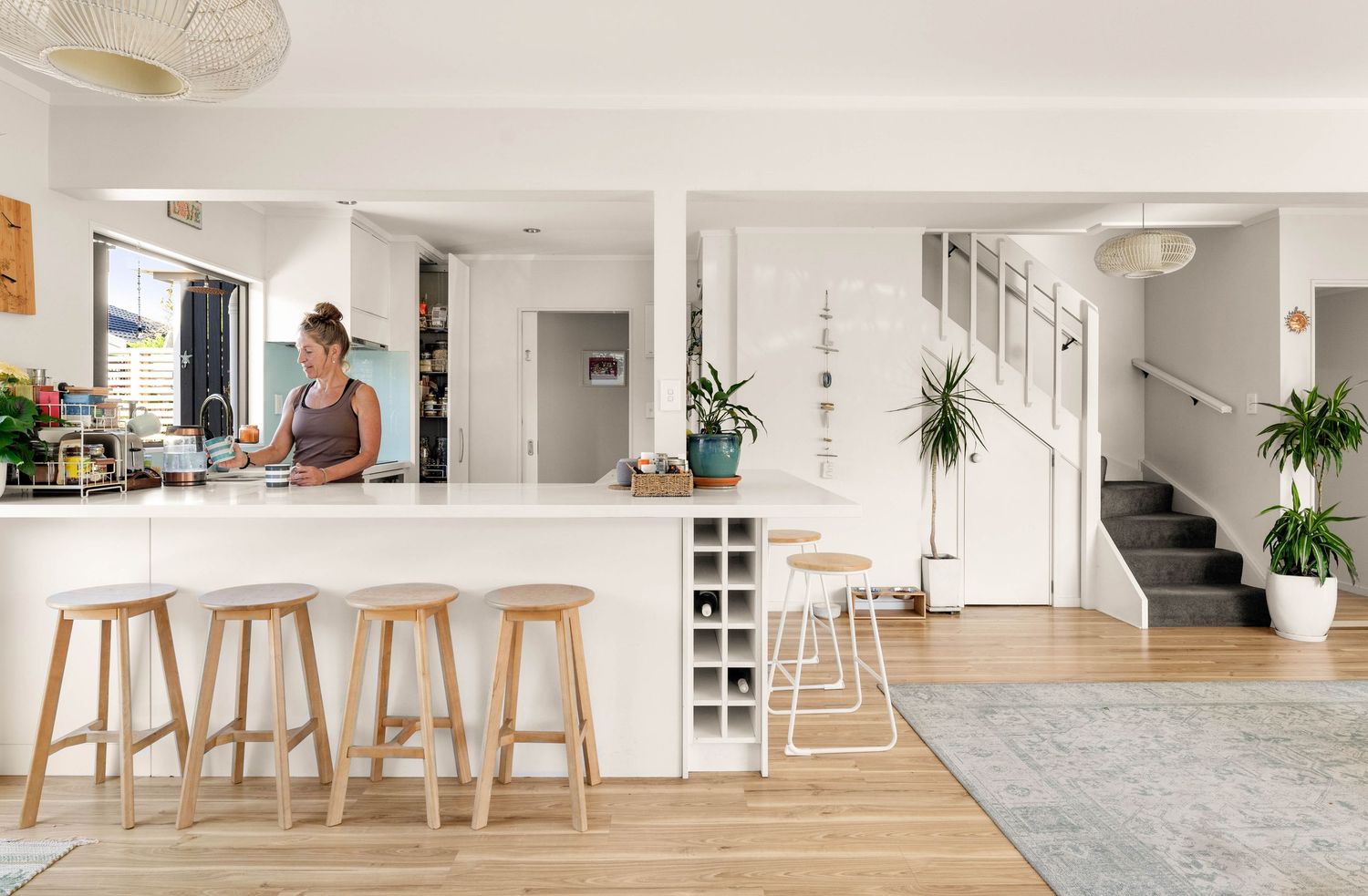 Modern open concept kitchen and living space with white walls, light wood floors, and minimal Scandinavian-style furniture.