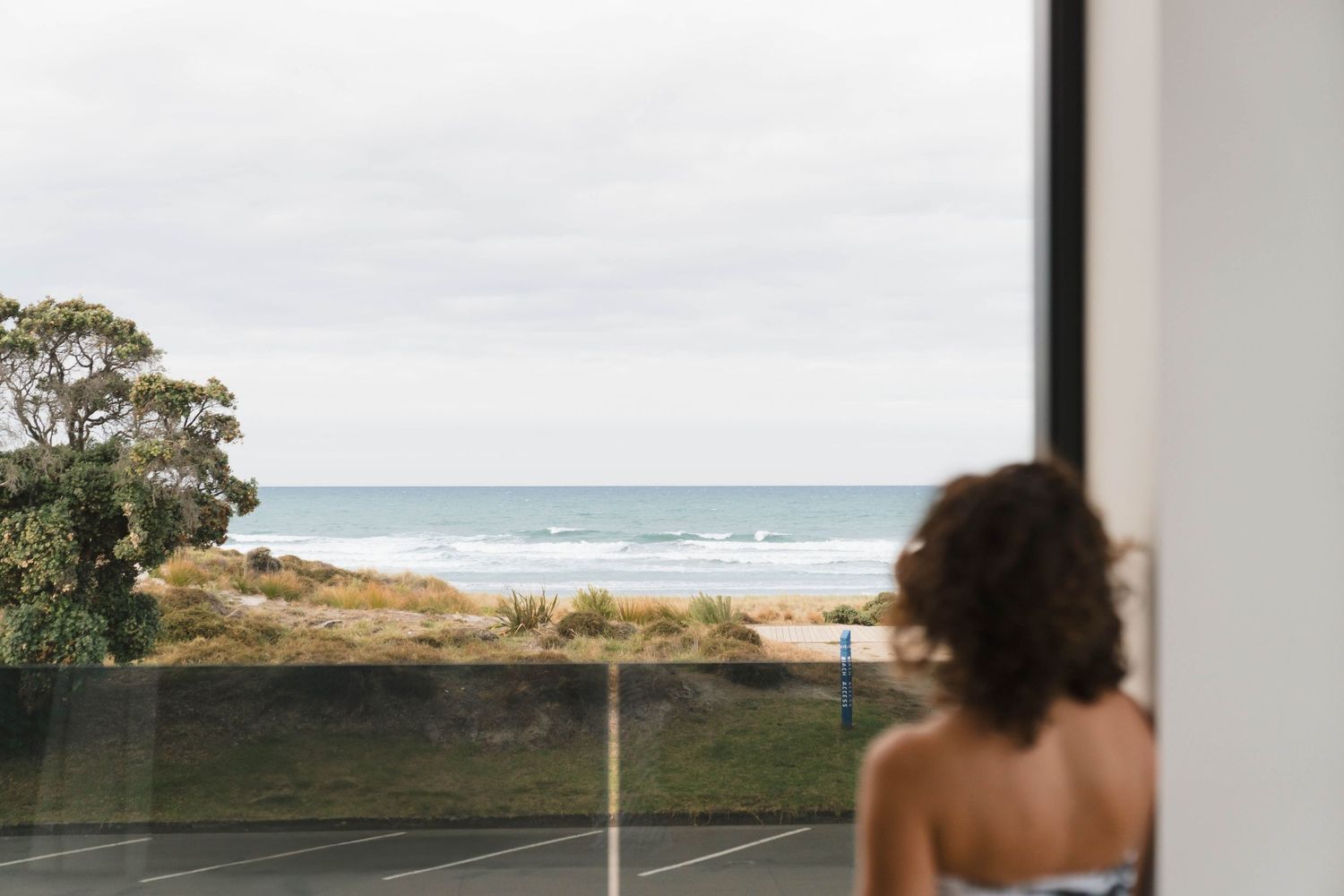 Interior view through large windows showcasing dramatic coastal scenery.