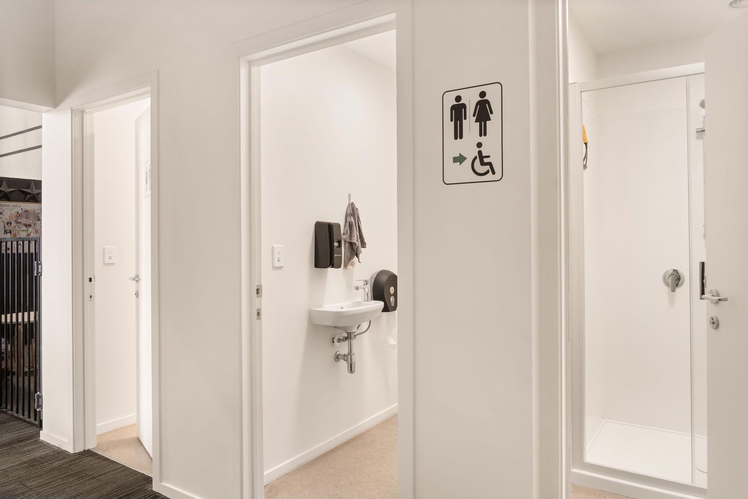 Modern hallway with multiple white doors and accessibility signage mounted on walls.
