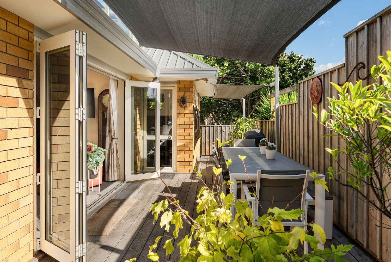 Modern brick home exterior with covered patio area and landscaped garden features in the backyard.
