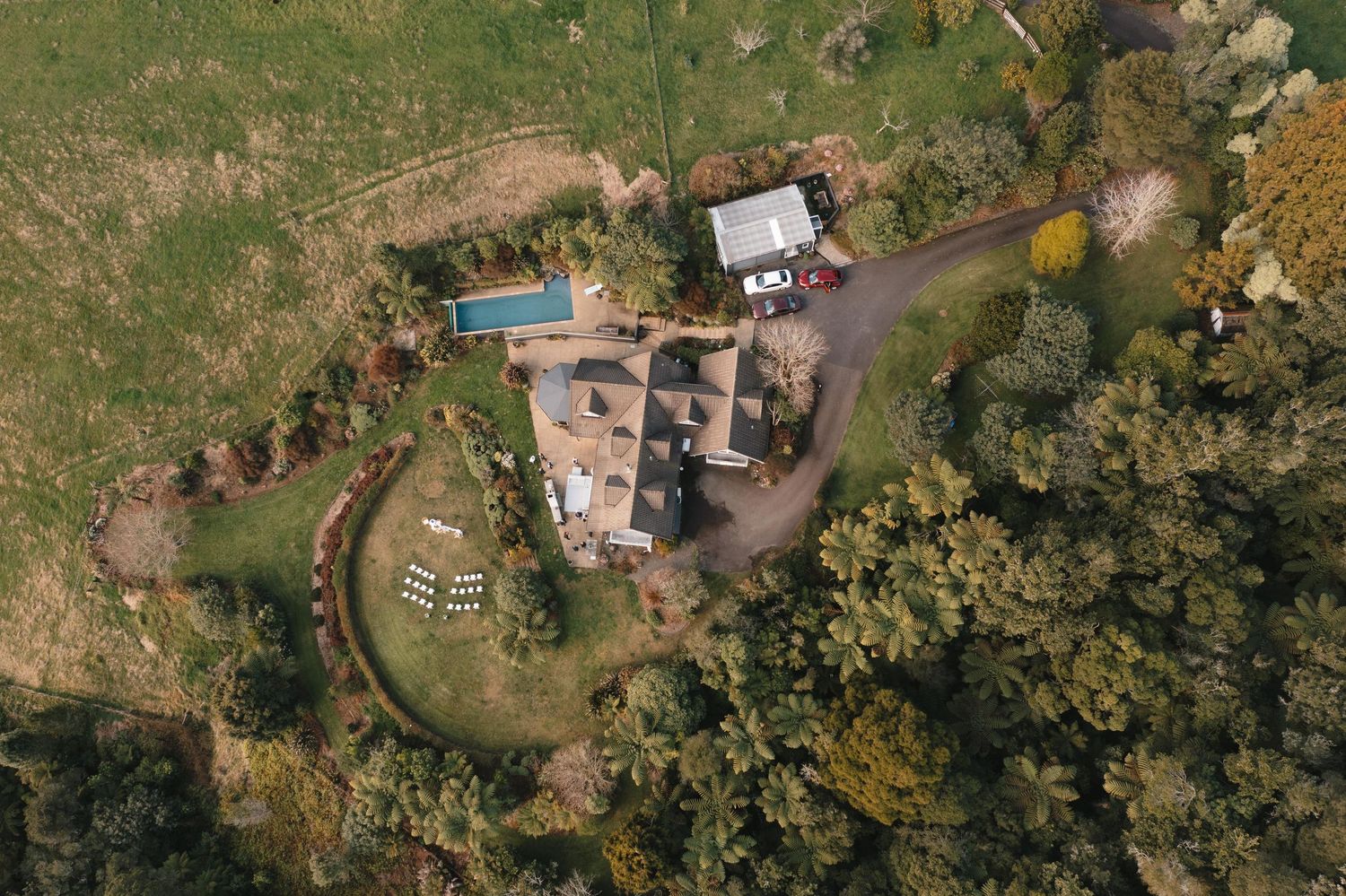 Aerial view of a country estate with swimming pool, circular garden, and autumn trees surrounding the property.