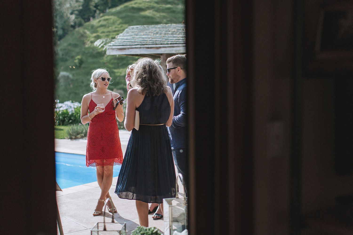 People mingling on an outdoor patio by a pool during a formal event or party in the summer.