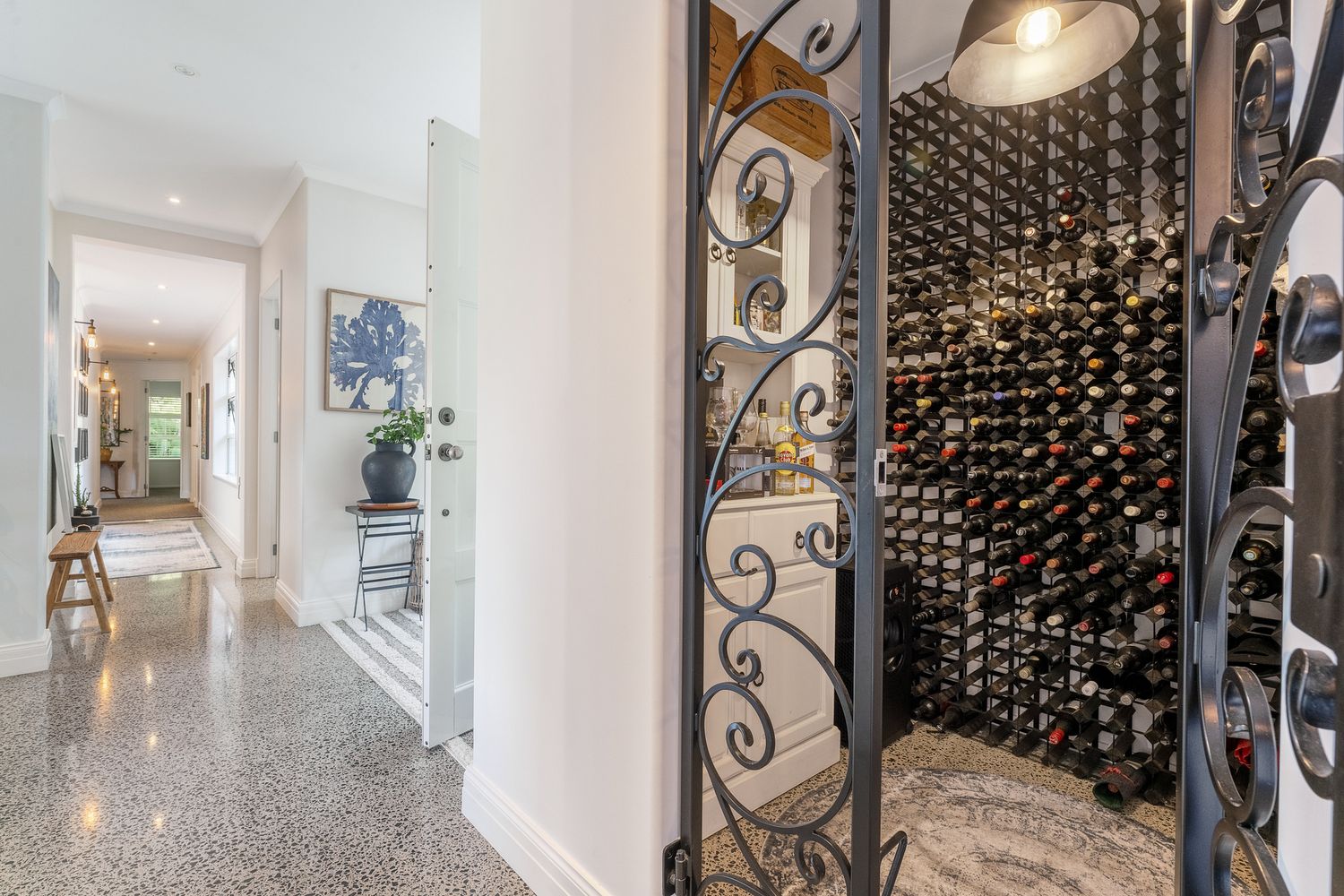 Luxurious wine cellar with ornate wrought iron doors and floor-to-ceiling bottle storage.